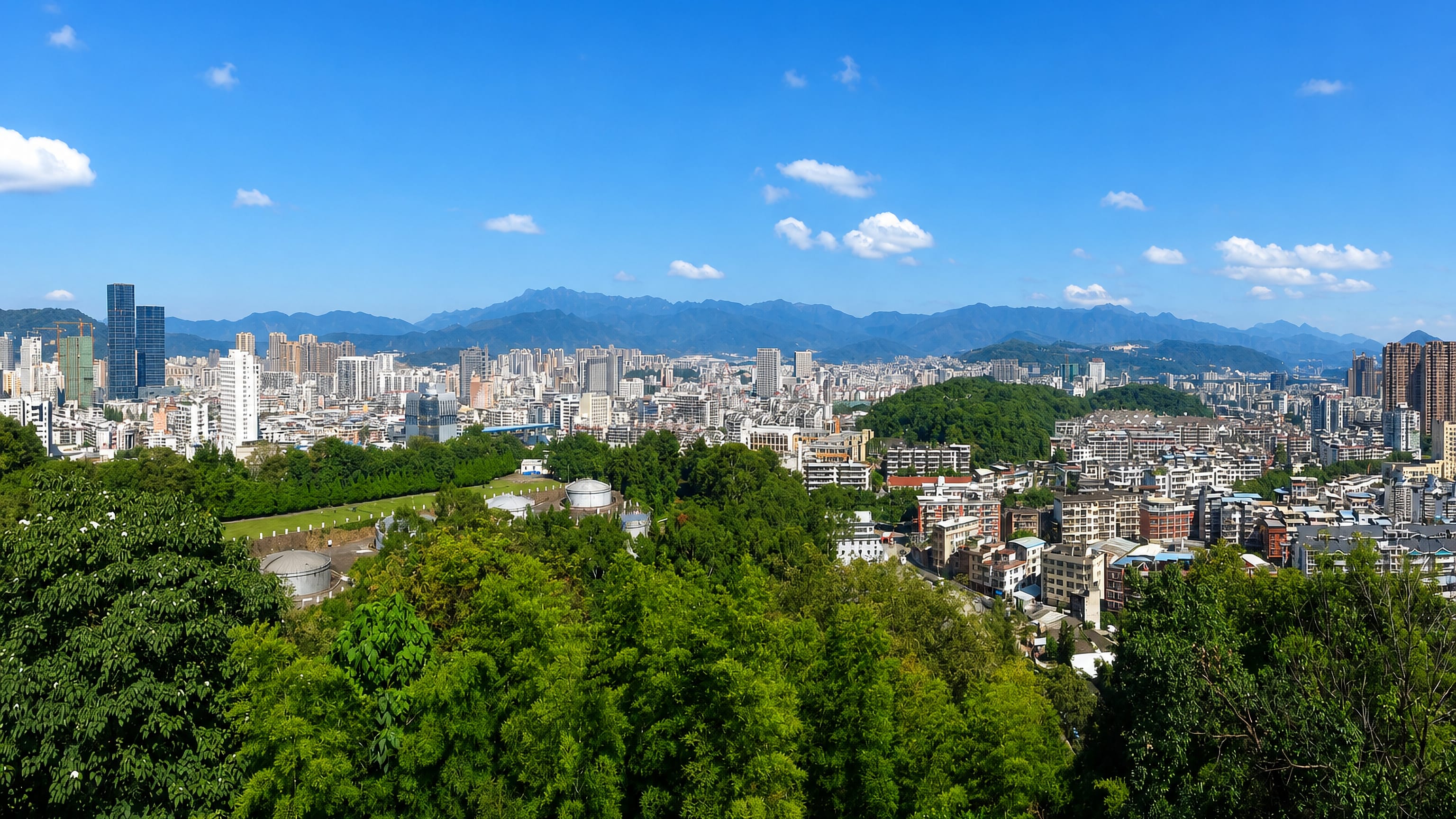 Longyan's dense city centre seen from a wooded hillside with Fujian's mountain ridges behind