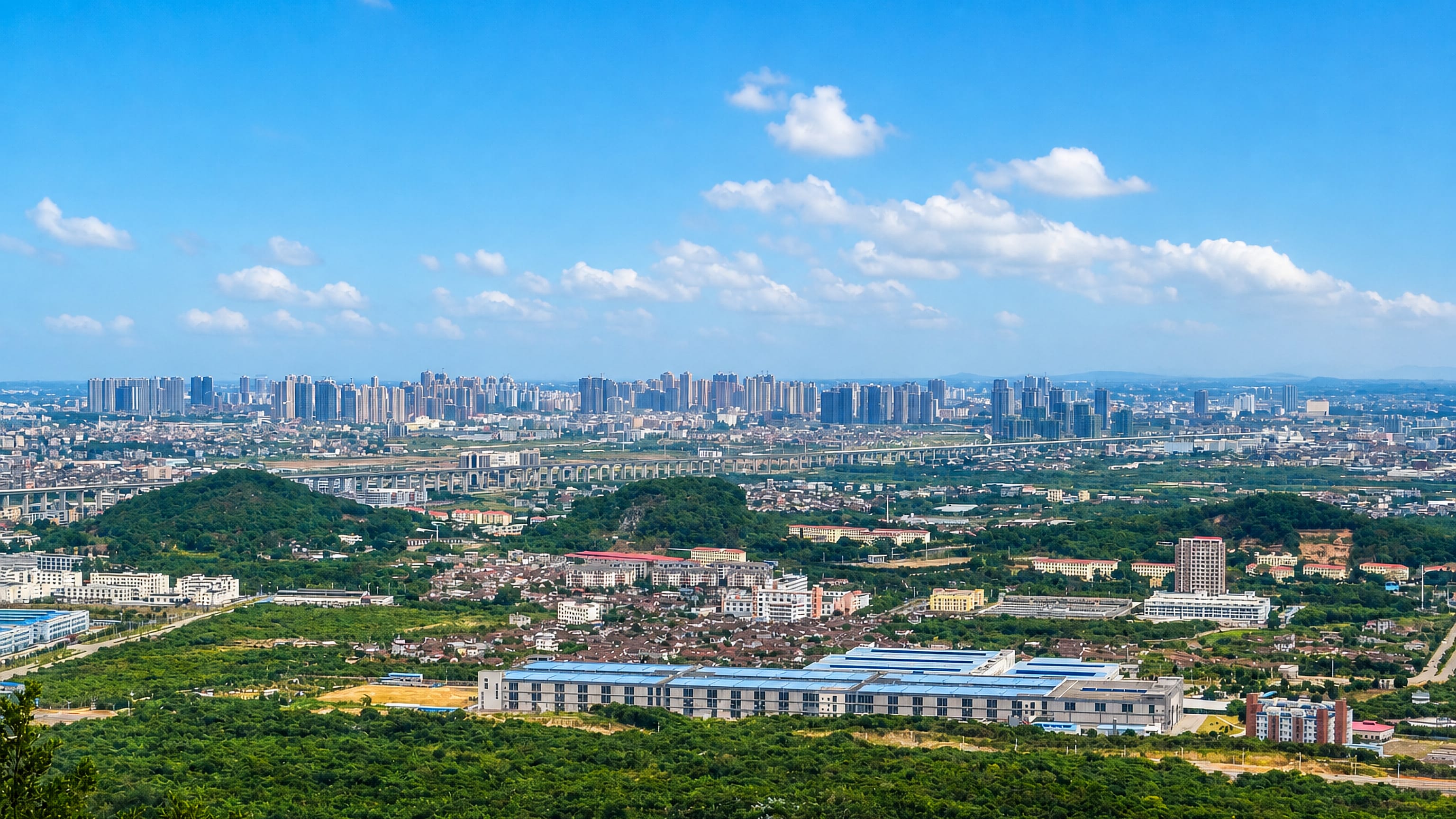 Hilltop view over Putian, Fujian, with high-rise districts spread across the plain beyond wooded ridges