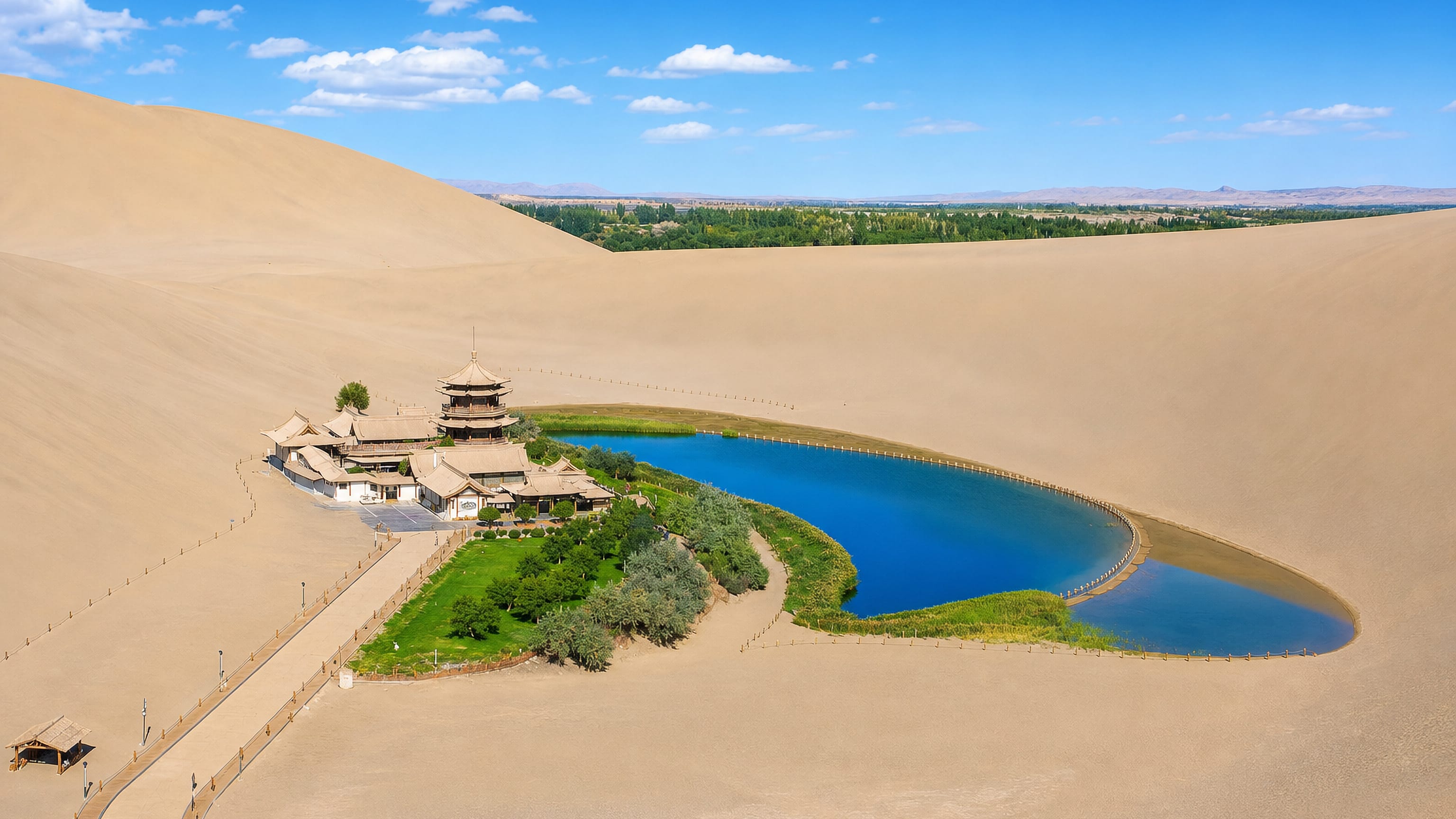 Crescent Lake and its pagoda temple ringed by the Mingsha sand dunes at Dunhuang, China, under a clear blue sky.