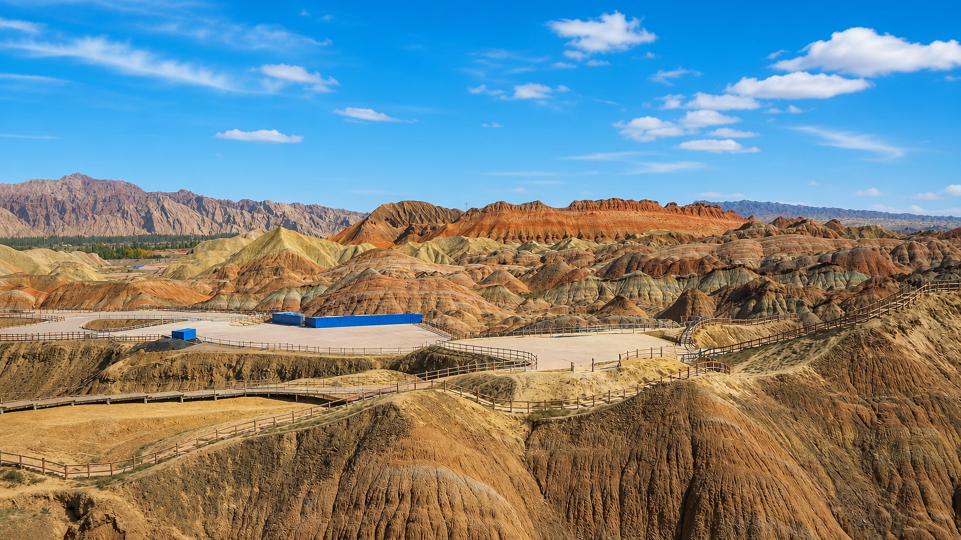 Banded red and ochre Danxia rock formations with visitor boardwalks at Zhangye, Gansu, China.