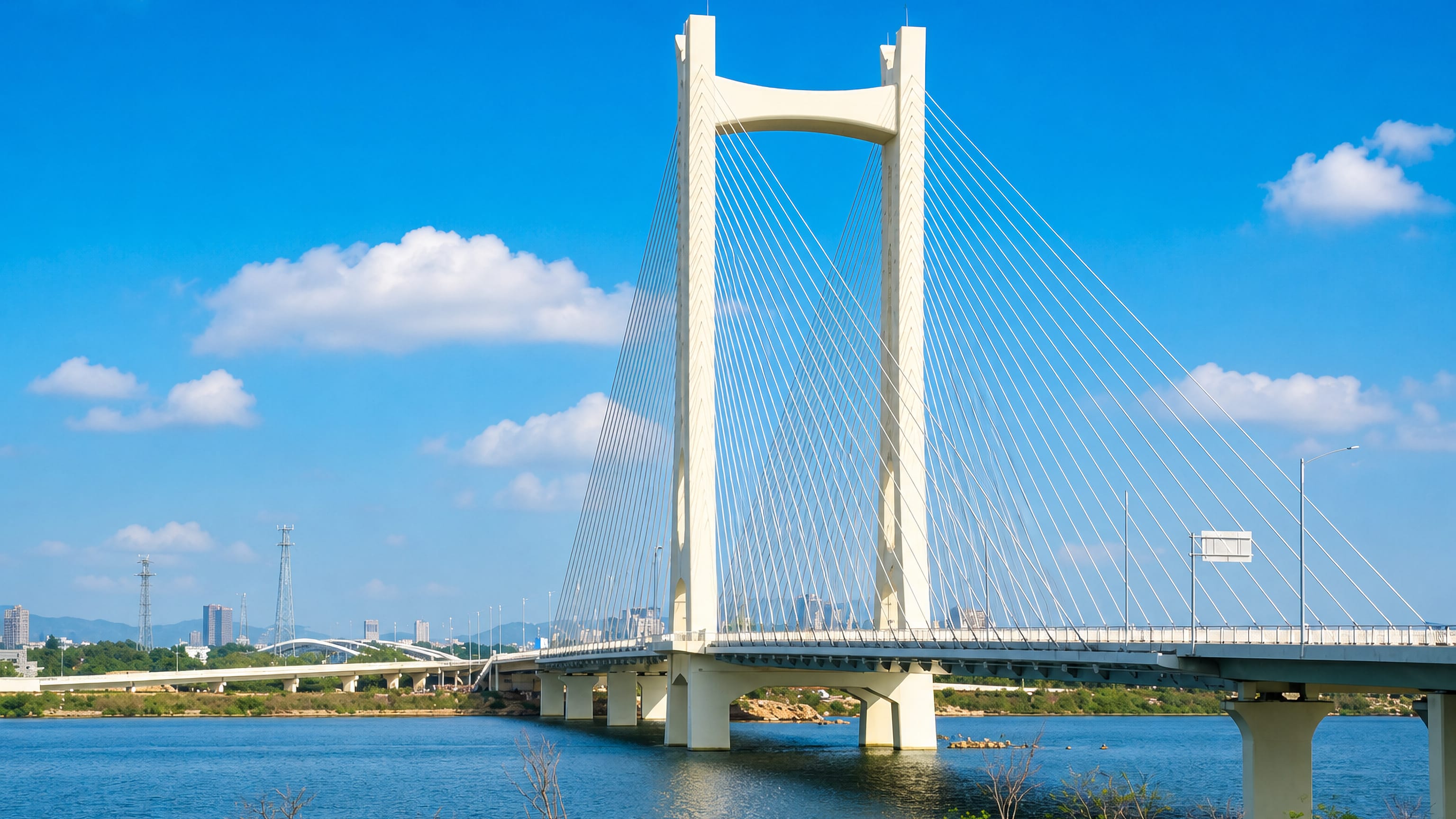 A white cable-stayed bridge spanning the Han River at Chaozhou, with the city skyline low on the horizon.
