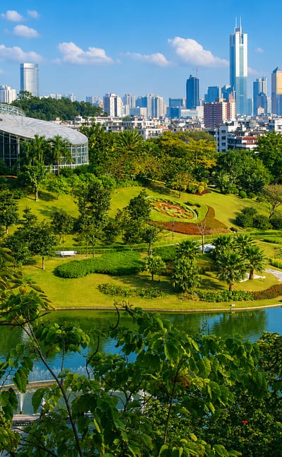Yuntai Garden's lake and glass conservatory in Baiyun District with the Guangzhou skyline behind.