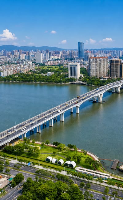 Aerial view of Guangzhou's Pearl River with an arched road bridge and high-rise skyline against distant hills