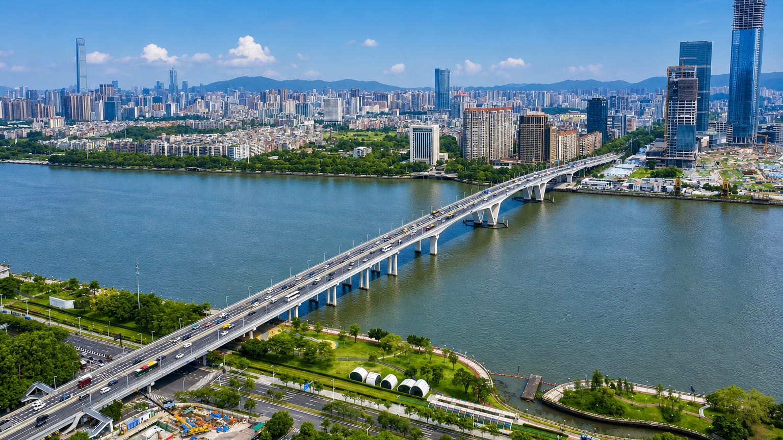 Aerial view of Guangzhou's Pearl River with an arched road bridge and high-rise skyline against distant hills