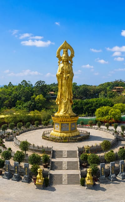 The giant golden Guanyin statue and pagoda at Lotus Hill in Guangzhou's Panyu District under a blue sky.