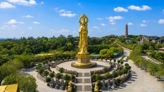 The giant golden Guanyin statue and pagoda at Lotus Hill in Guangzhou's Panyu District under a blue sky.