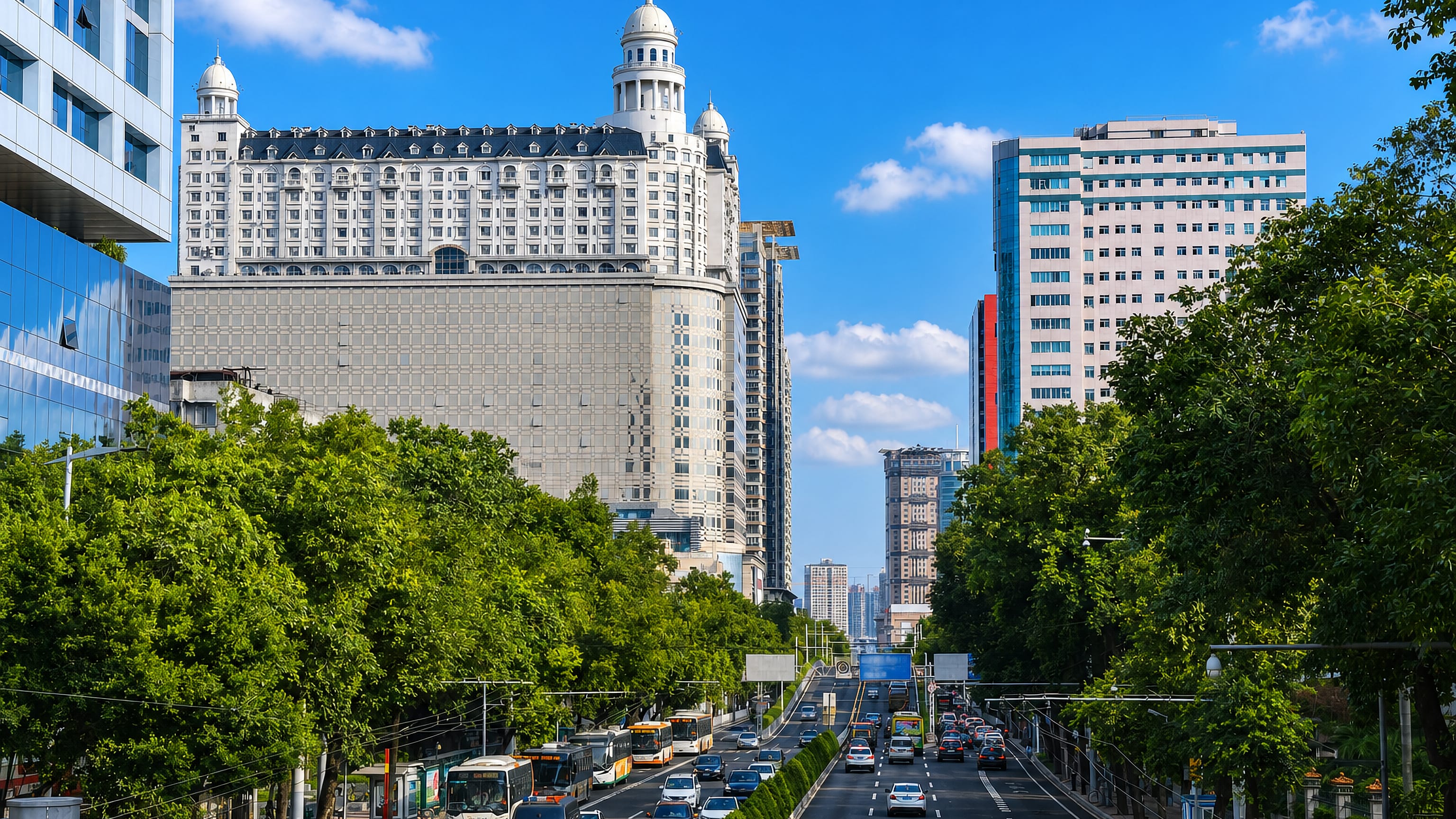 A tree-lined boulevard in Yuexiu District, Guangzhou, below a white domed high-rise.