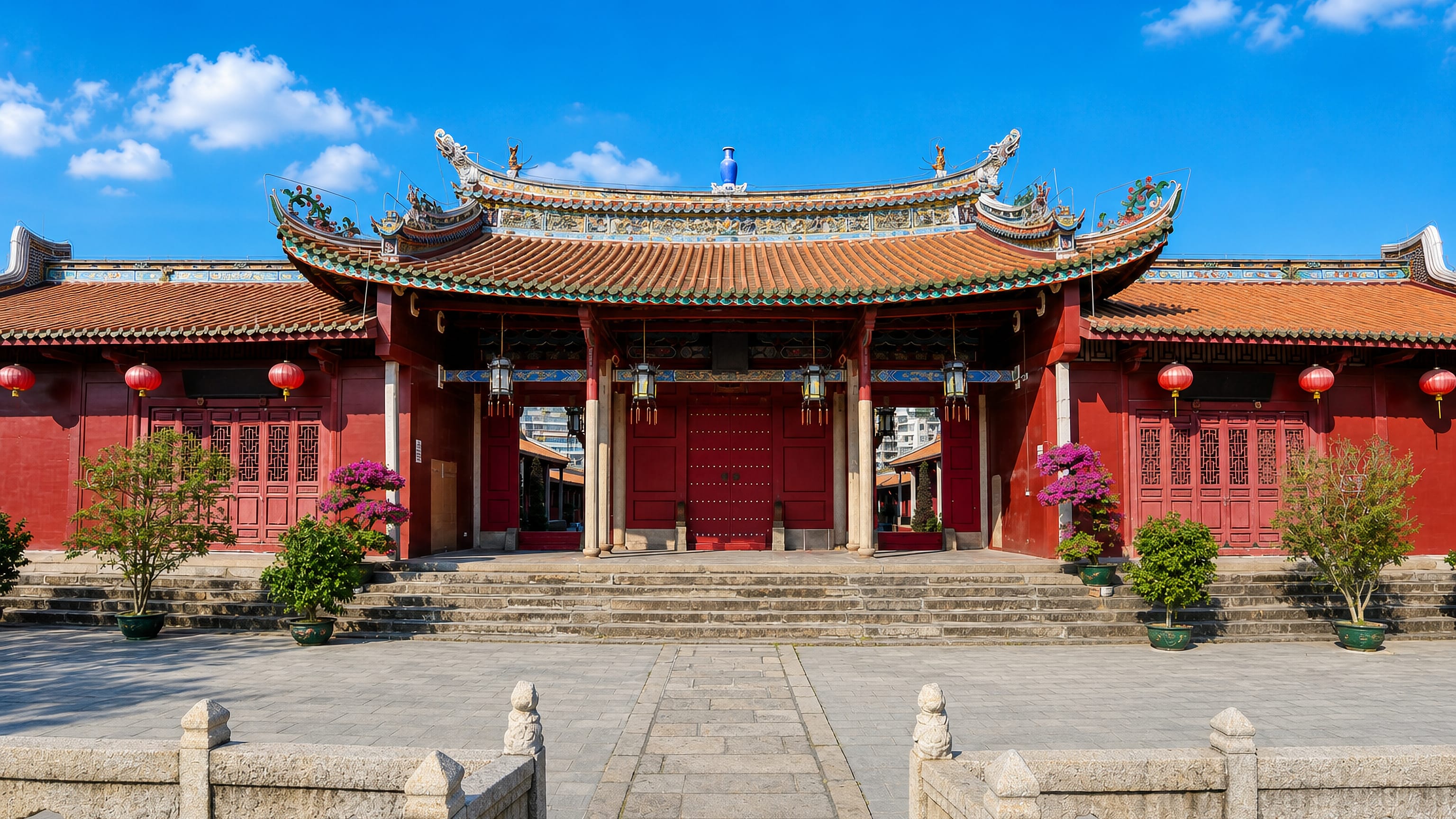 Red-walled Confucian temple hall with ornate tiled roofs and a stone forecourt in Jieyang, Guangdong.
