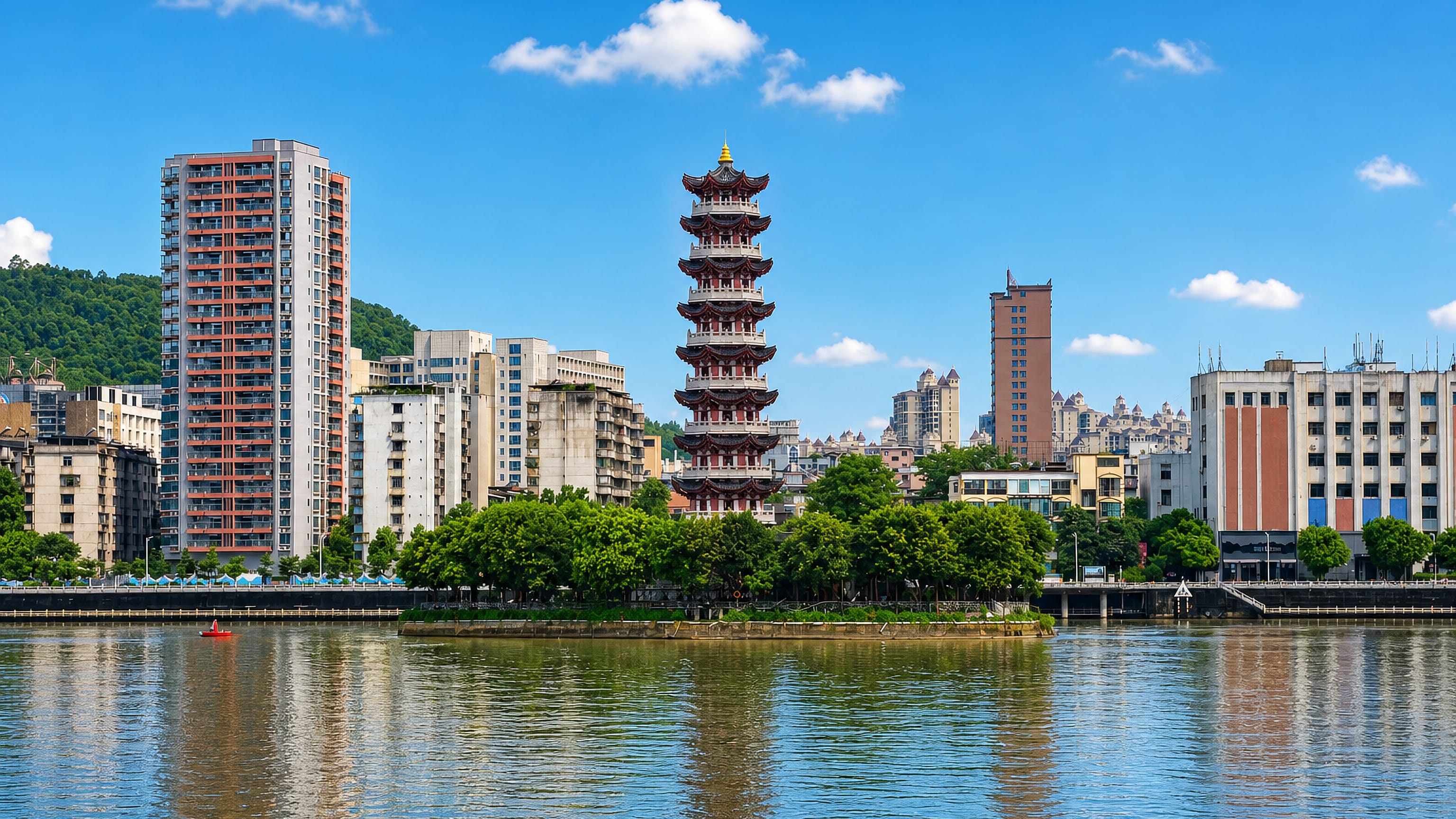 Riverfront in Shaoguan, China, with a tall tiered pagoda and apartment towers backed by green hills.