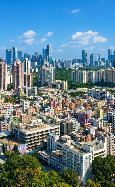Dense high-rise cityscape with a supertall tower and green parkland in Shenzhen, China.