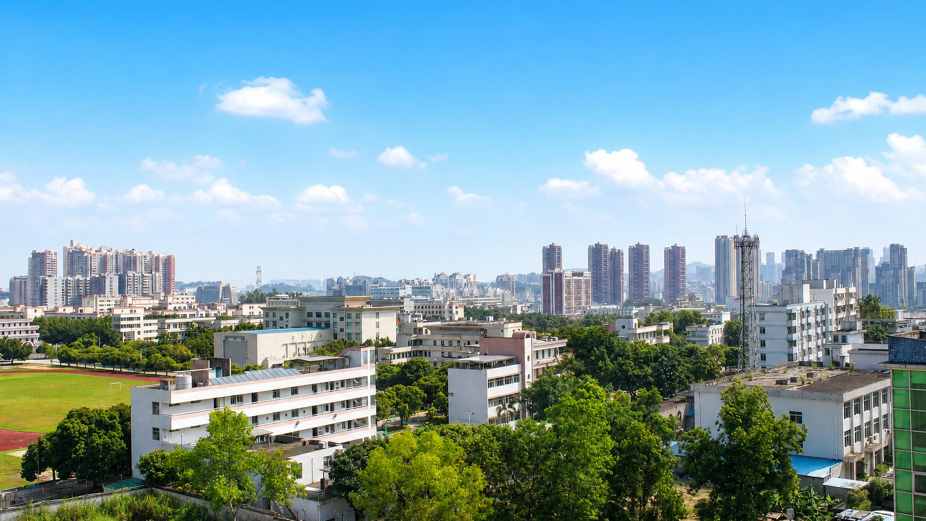 High-rise residential towers rising behind low-rise blocks and school grounds in Longhua District, Shenzhen.