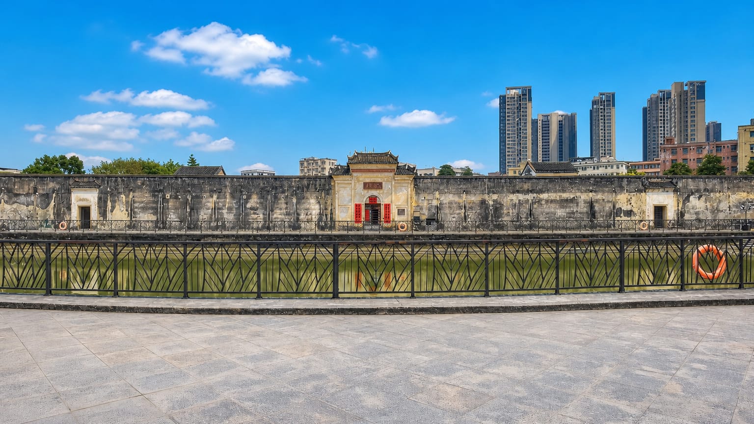 Historic walled ancestral hall with a decorated gatehouse fronting modern high-rise towers across water in Pingshan District, Shenzhen.