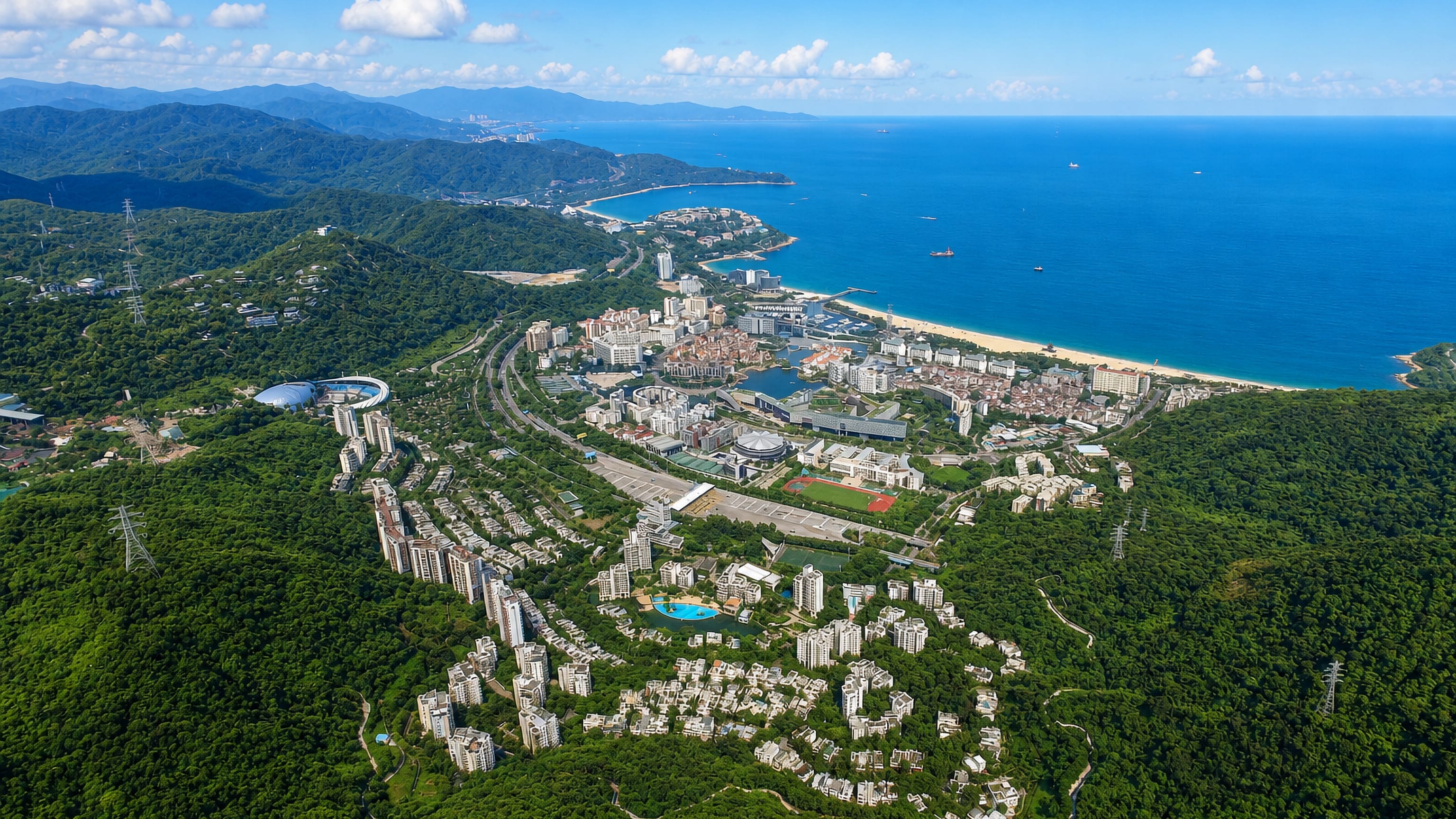 Forested hills sweeping down to a beachfront resort district and the South China Sea in Yantian, Shenzhen.
