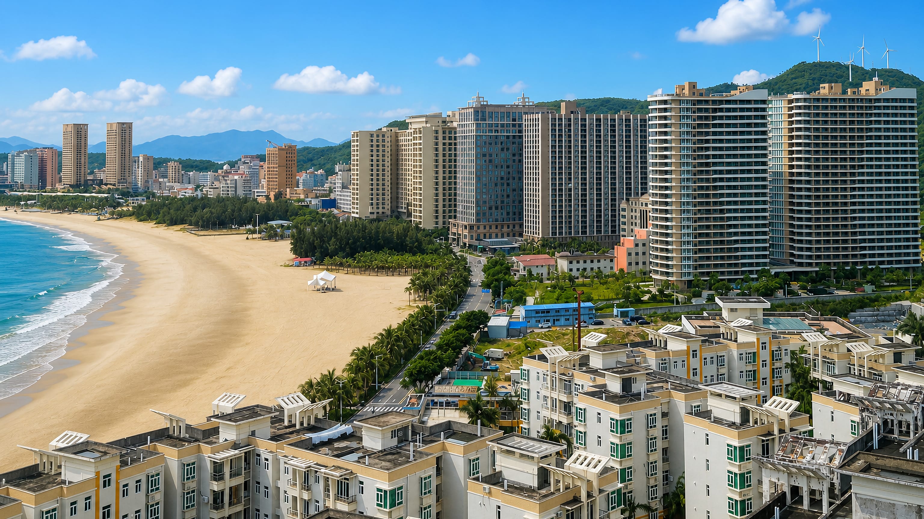 Curving sandy beach backed by high-rise apartment towers and wind-turbine hills at Yangjiang, China.