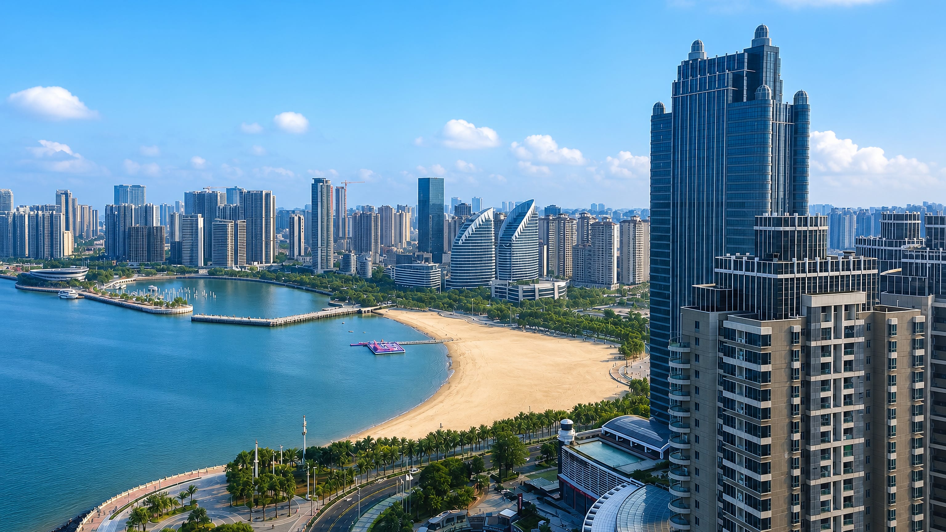 Zhanjiang, China, with a crescent sand beach, palm-lined seafront boulevard and high-rise towers around the bay.