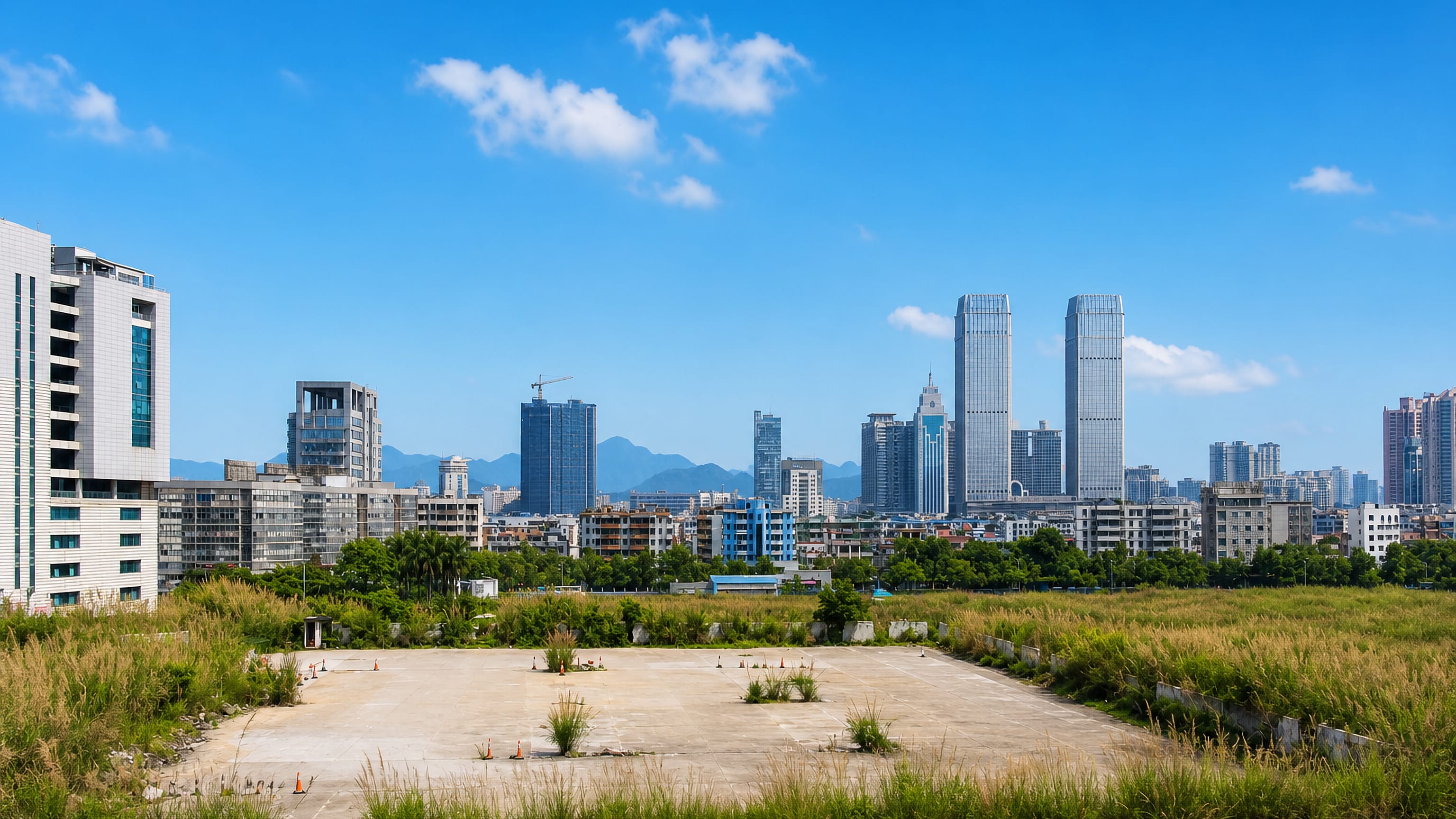 Zhongshan's high-rise skyline and twin towers rising beyond a vacant lot, Guangdong, China.