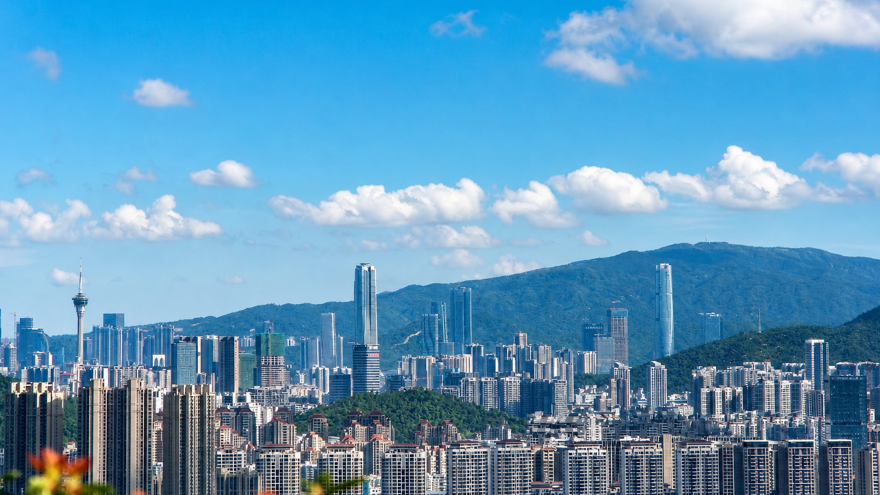 High-rise apartment and office towers of Zhuhai, China, rising against forested coastal hills.