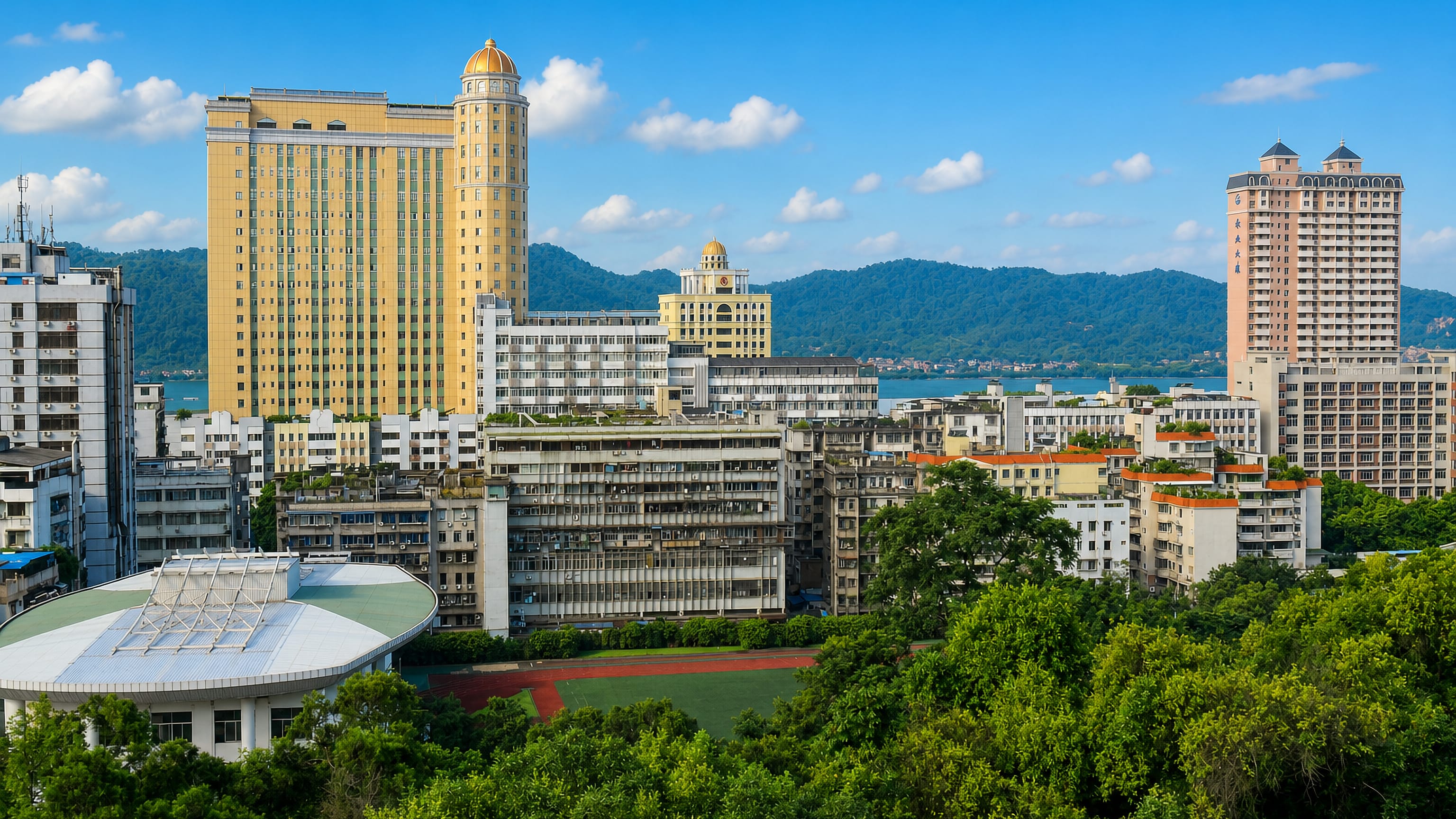 Wuzhou, Guangxi, with gold-domed high-rises and dense apartment blocks below forested hills and the river.