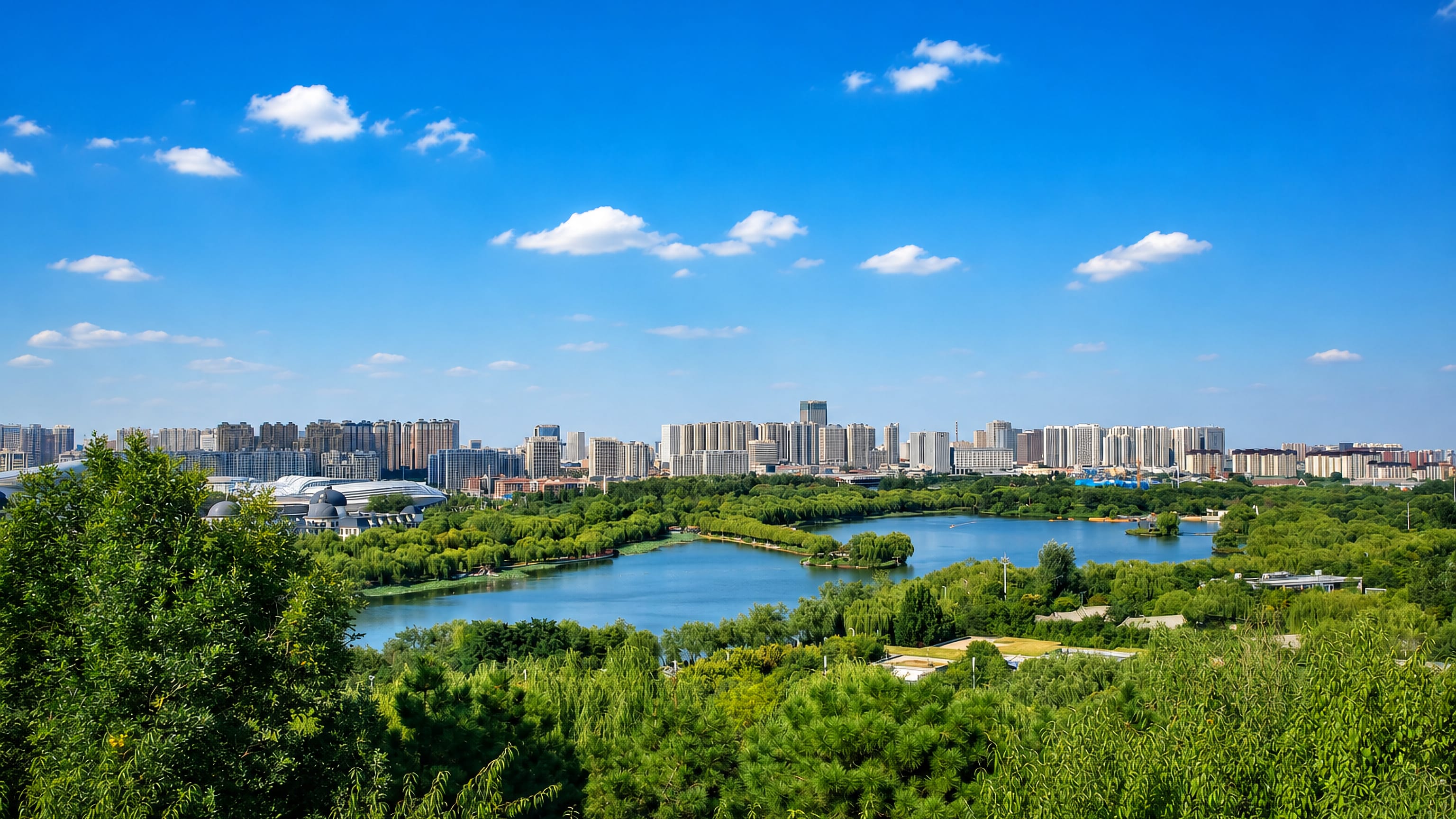 Tangshan, China, seen across a willow-fringed park lake toward a long skyline of white residential towers.
