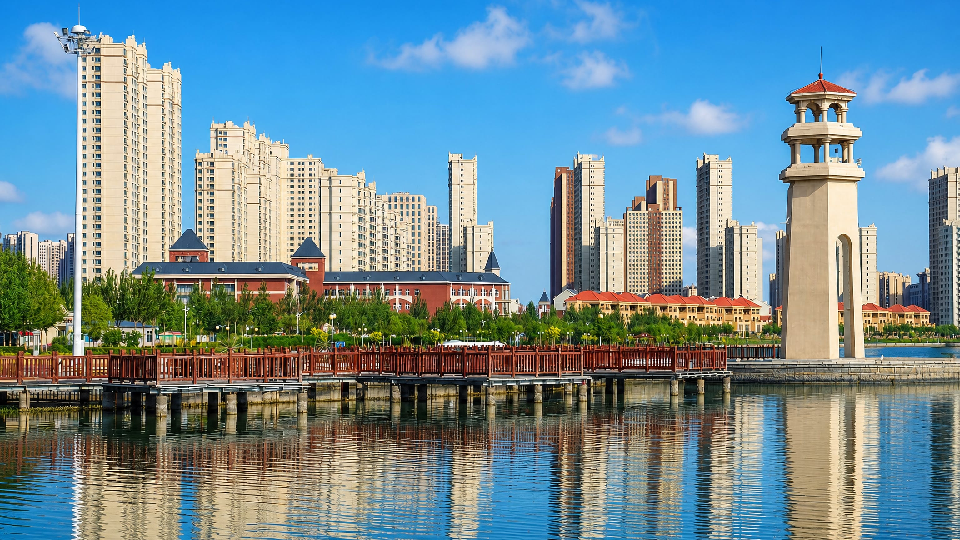 Lakeside boardwalk and lighthouse tower before high-rise apartment blocks in Daqing, Heilongjiang
