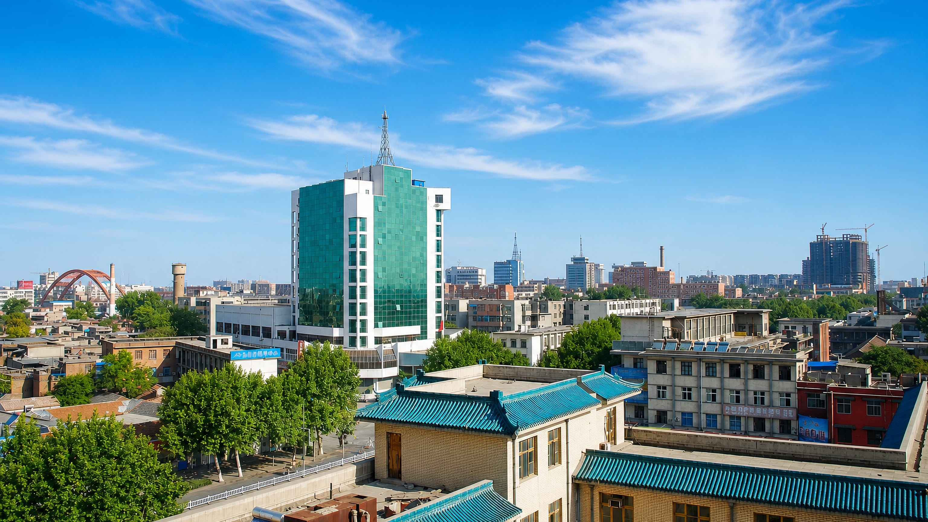 Anyang rooftops with blue-tiled traditional buildings, a green glass tower and the wider city skyline beyond