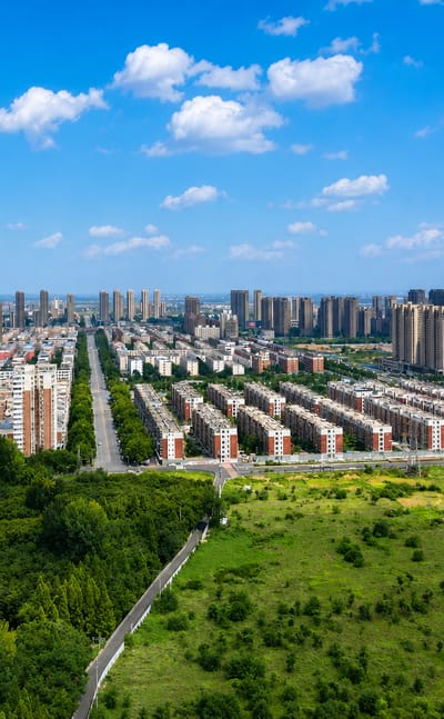 Aerial view of Luoyang's residential high-rises bordered by green fields and woodland.