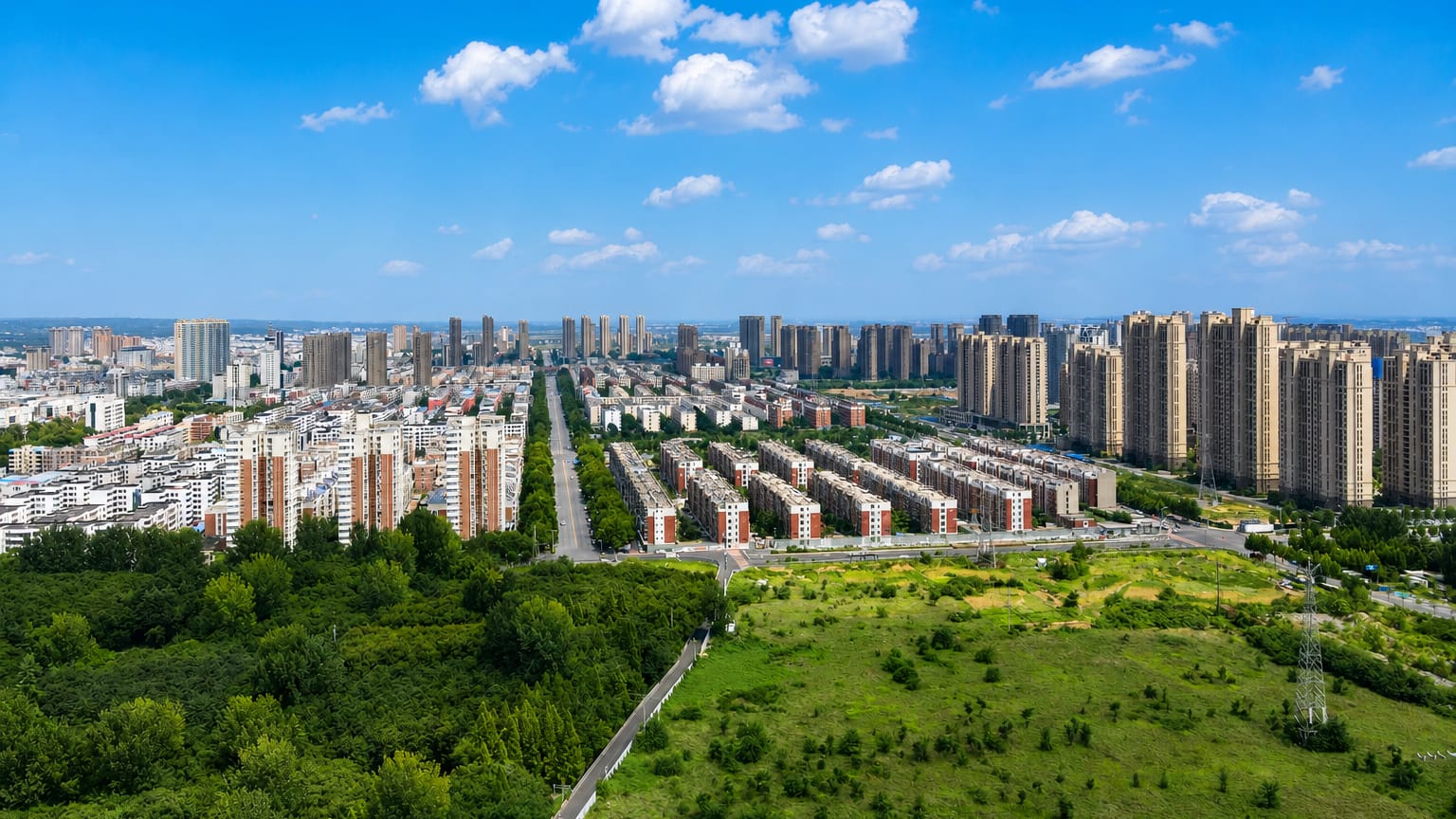 Aerial view of Luoyang's residential high-rises bordered by green fields and woodland.