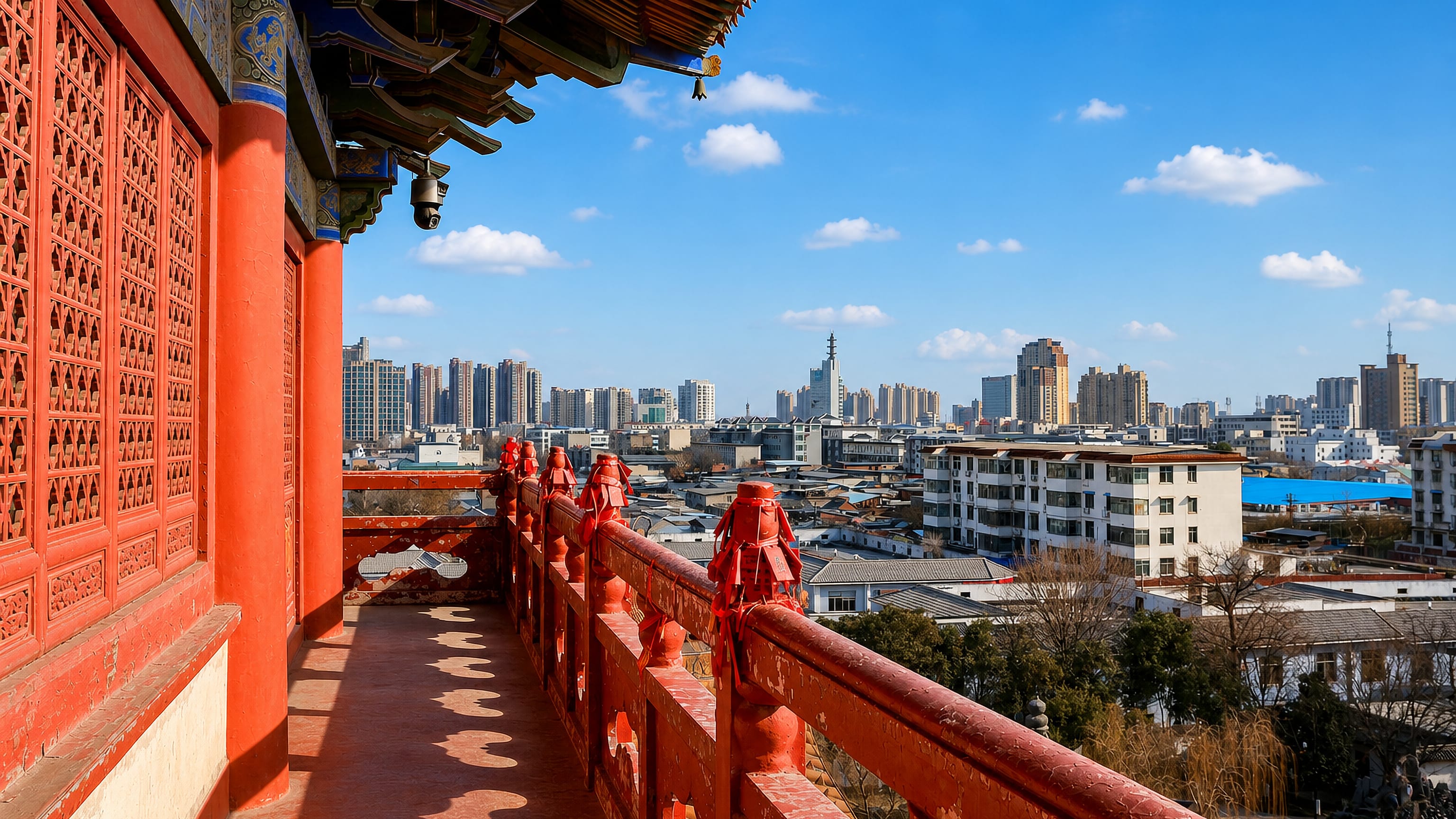 City skyline of Xuchang, China, framed by the red railings and eaves of a traditional temple tower.