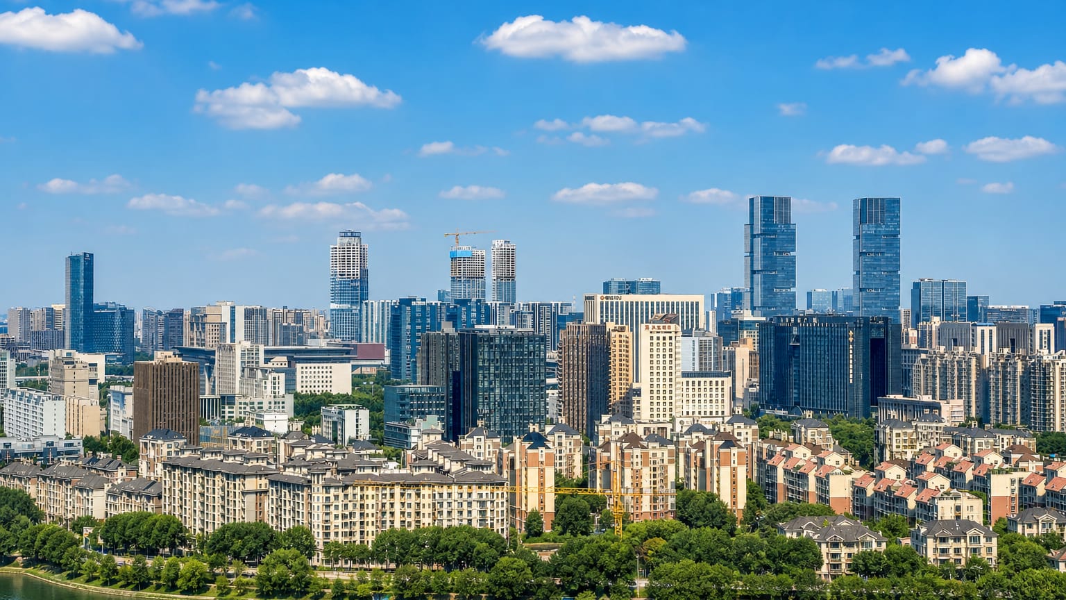 Riverside skyline of Zhengzhou with residential blocks and central high-rise towers under a blue sky.