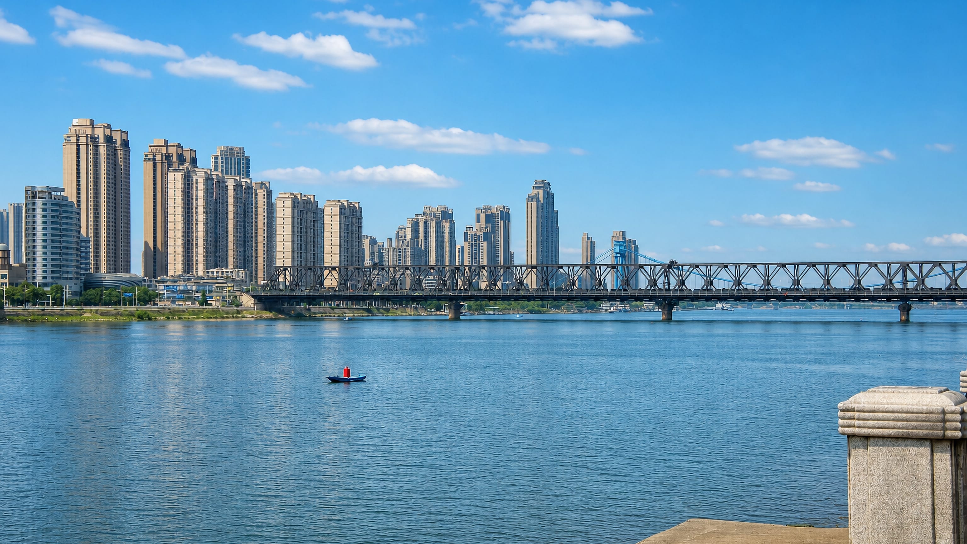 The Han River at Xiangyang, China, with a steel truss bridge and riverside high-rise towers.