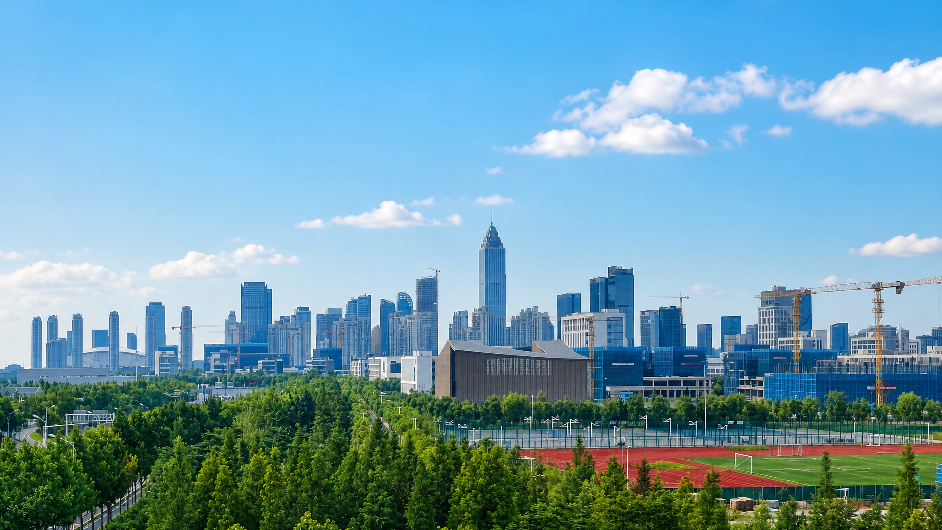 Nantong's high-rise CBD skyline rising beyond a belt of parkland and a sports field on a clear day.