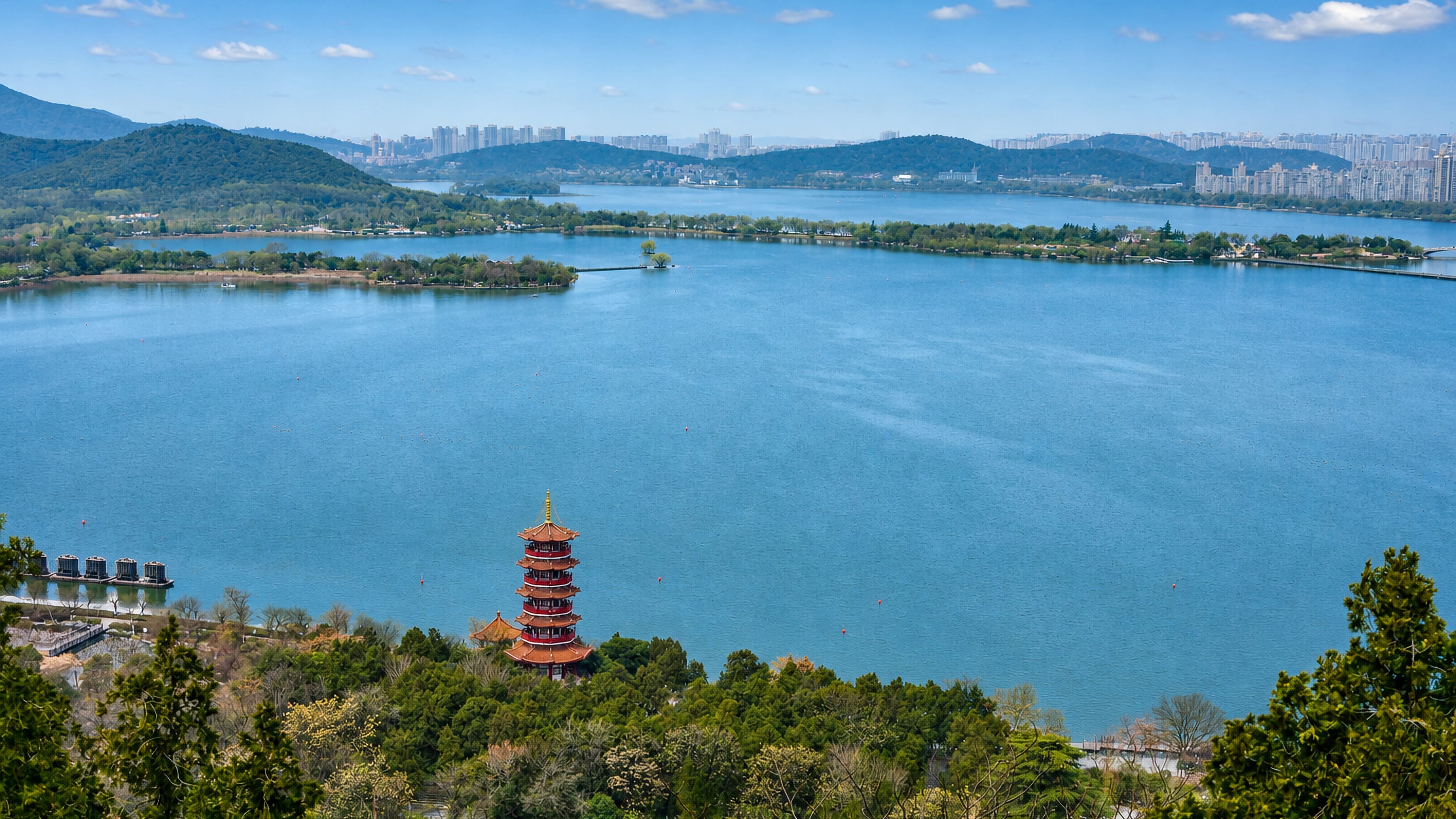 Yunlong Lake and its lakeside pagoda at Tongshan, Xuzhou, with wooded hills and the city skyline beyond.
