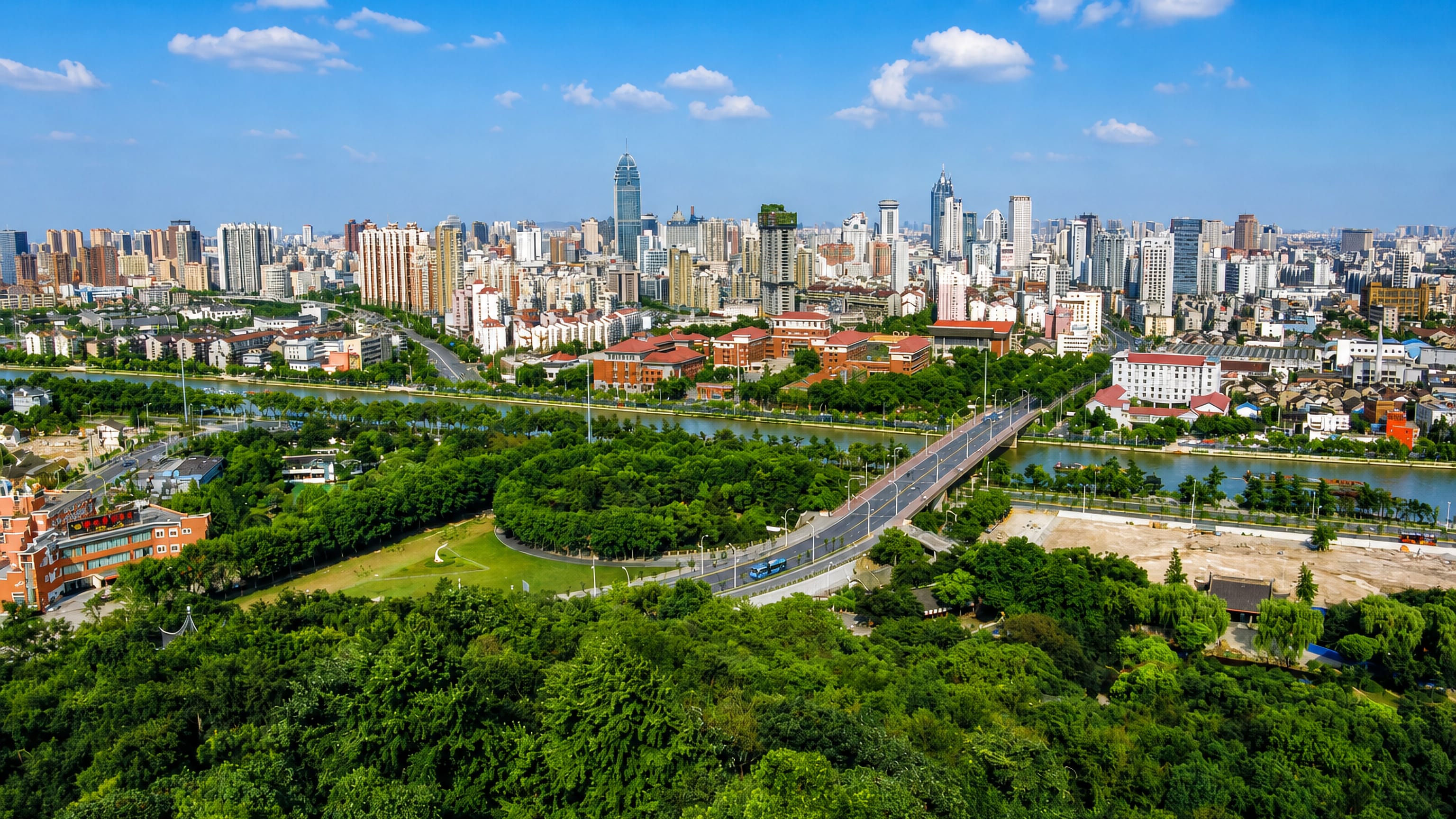 Wuxi skyline of high-rise towers rising beyond the tree-lined Grand Canal and a green riverside park