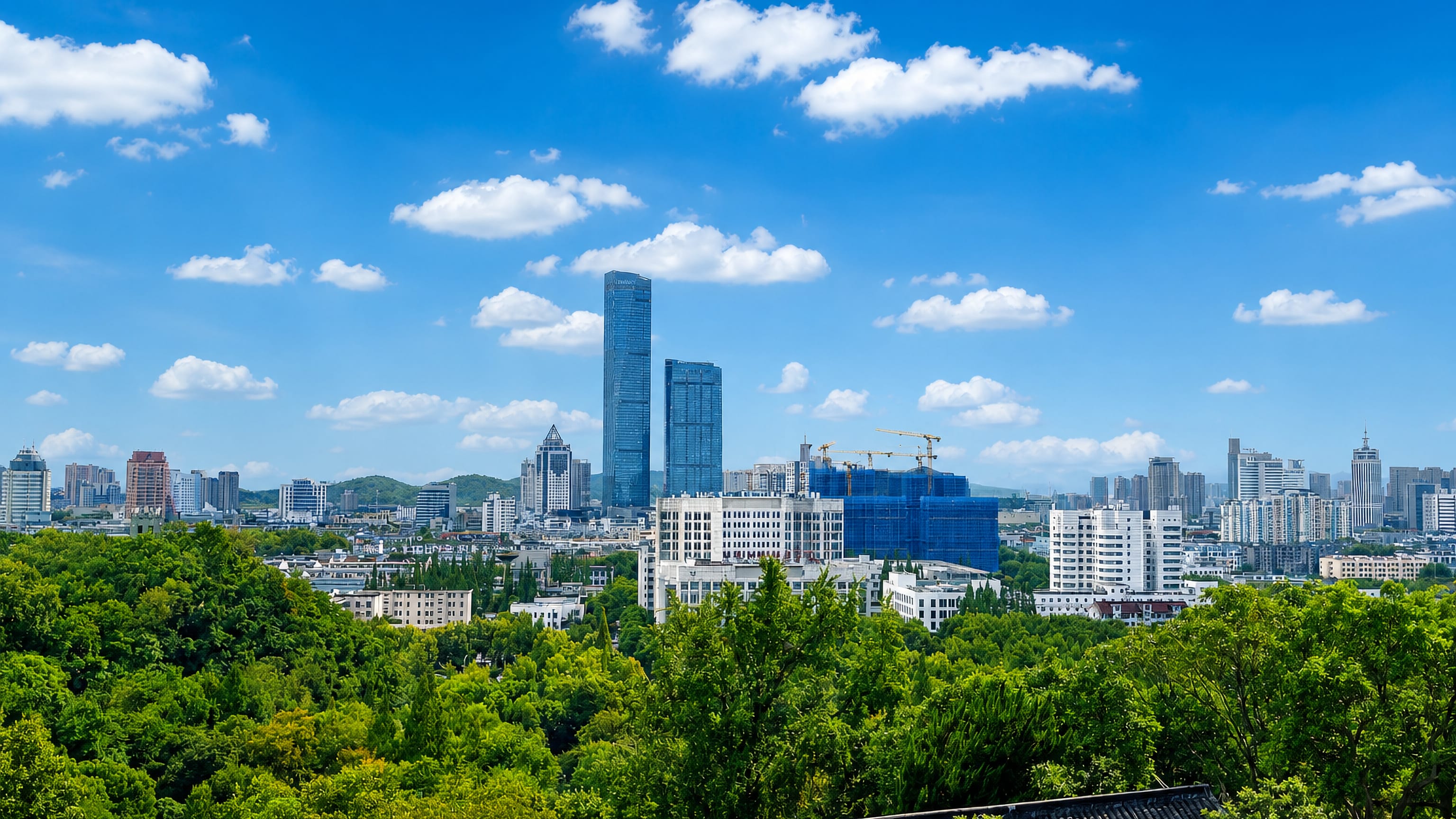 Zhenjiang skyline in Jiangsu, with a glass tower above tree-filled streets and a tiled roof in the foreground.