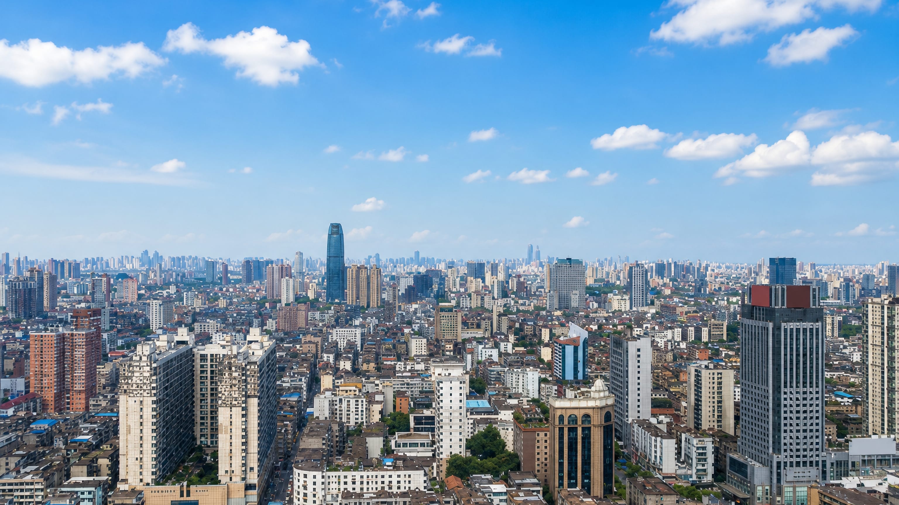 Dense high-rise skyline of Nanchang, Jiangxi, under a blue summer sky stretching to distant towers.