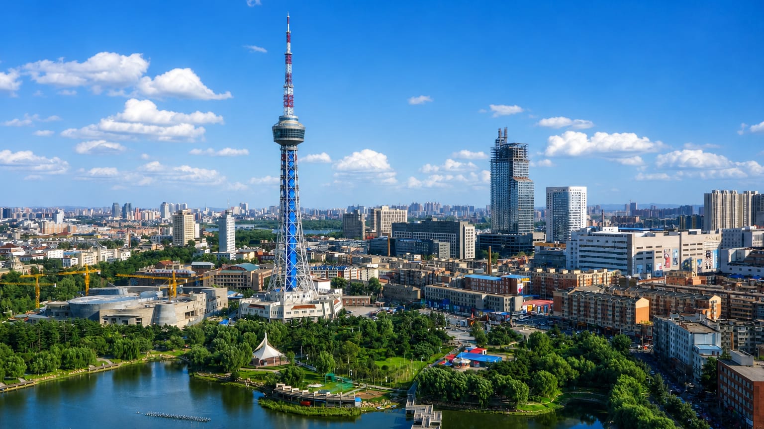 Changchun's lattice TV tower above a lakeside park and city skyline under a bright blue sky.