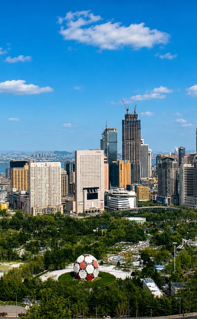 Dalian skyline with high-rise towers, a giant football sculpture and a Ferris wheel by the sea