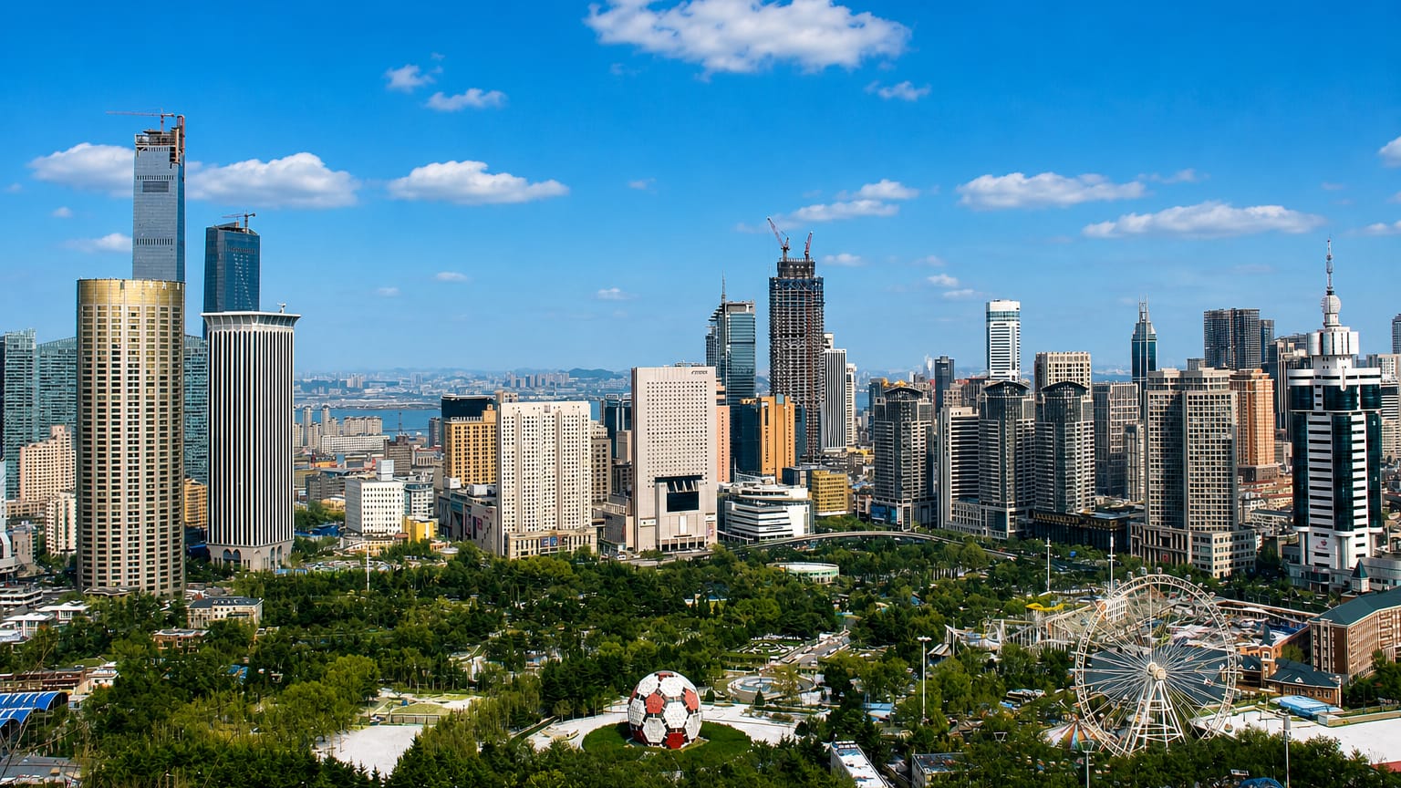 Dalian skyline with high-rise towers, a giant football sculpture and a Ferris wheel by the sea