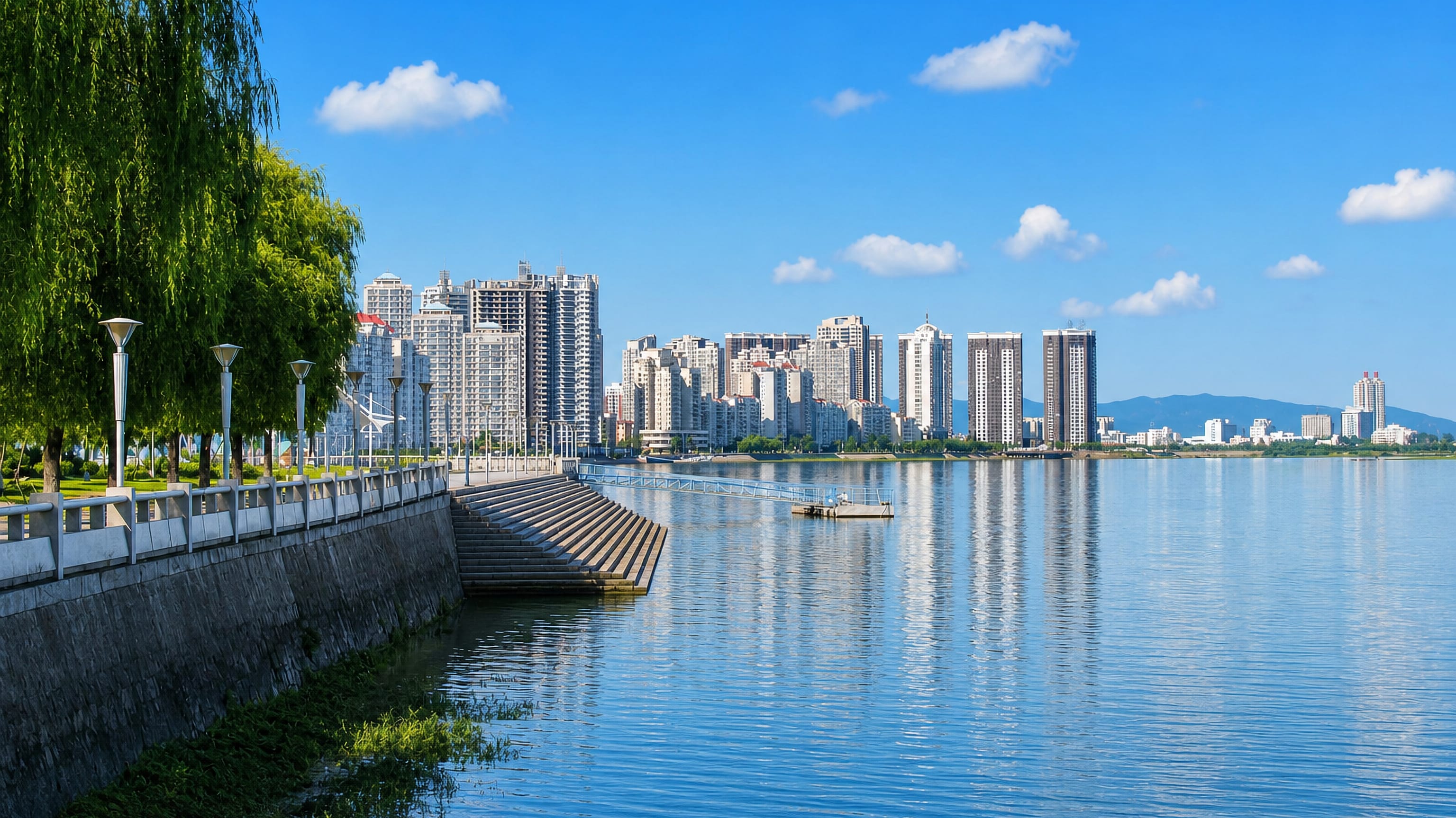Riverside promenade on the Yalu at Dandong, China, facing the city's high-rise waterfront and hills