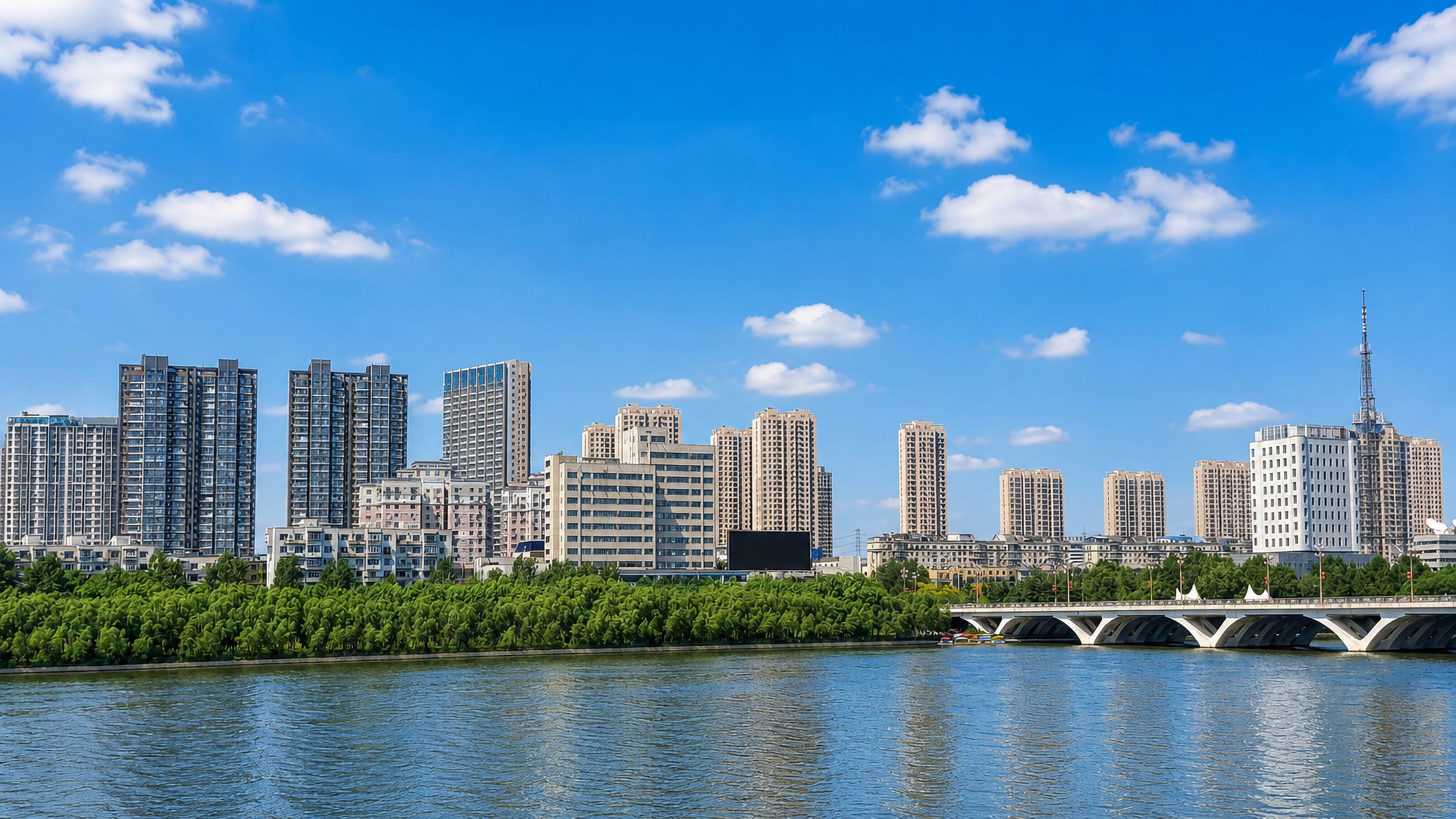 Riverfront high-rises, an arched bridge and a broadcast tower along the Hun River in Fushun, Liaoning