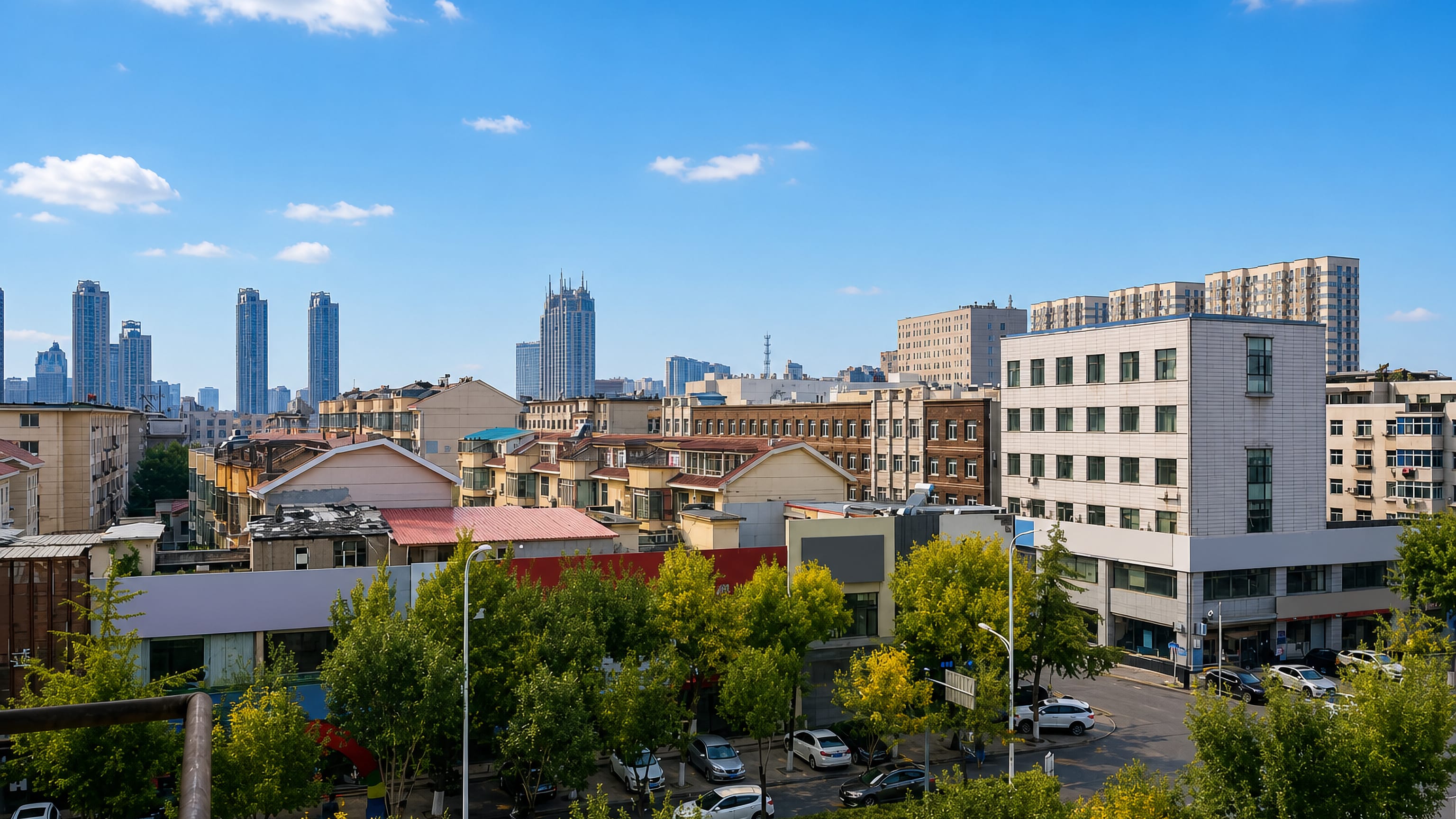 Rooftop view across Liaoyang's older housing blocks toward distant high-rise towers in Liaoning.
