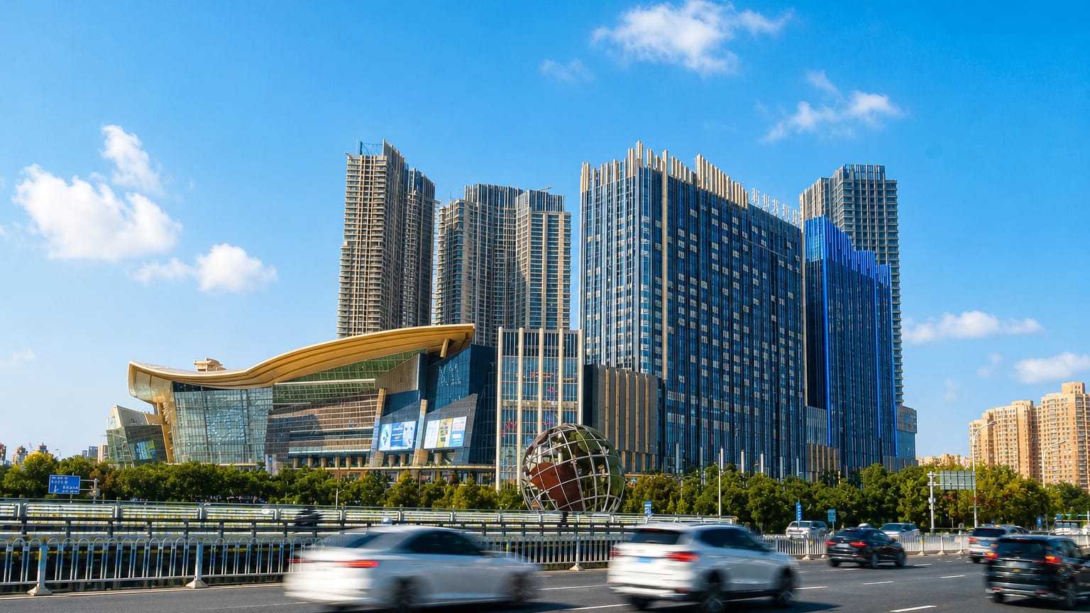 Shenyang's high-rise district with a globe sculpture and curved-roof arts hall beside a busy avenue.