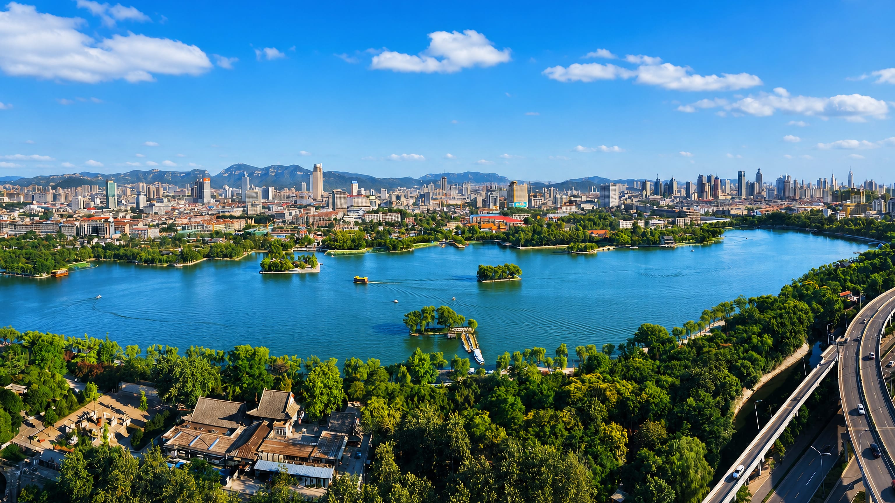 Daming Lake fringed with willows in front of Jinan's downtown skyline and the Shandong hills beyond.
