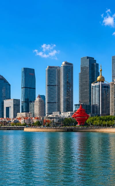Qingdao skyline behind May Fourth Square with the red 'May Wind' sculpture on the seafront promenade.