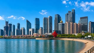 Qingdao skyline behind May Fourth Square with the red 'May Wind' sculpture on the seafront promenade.