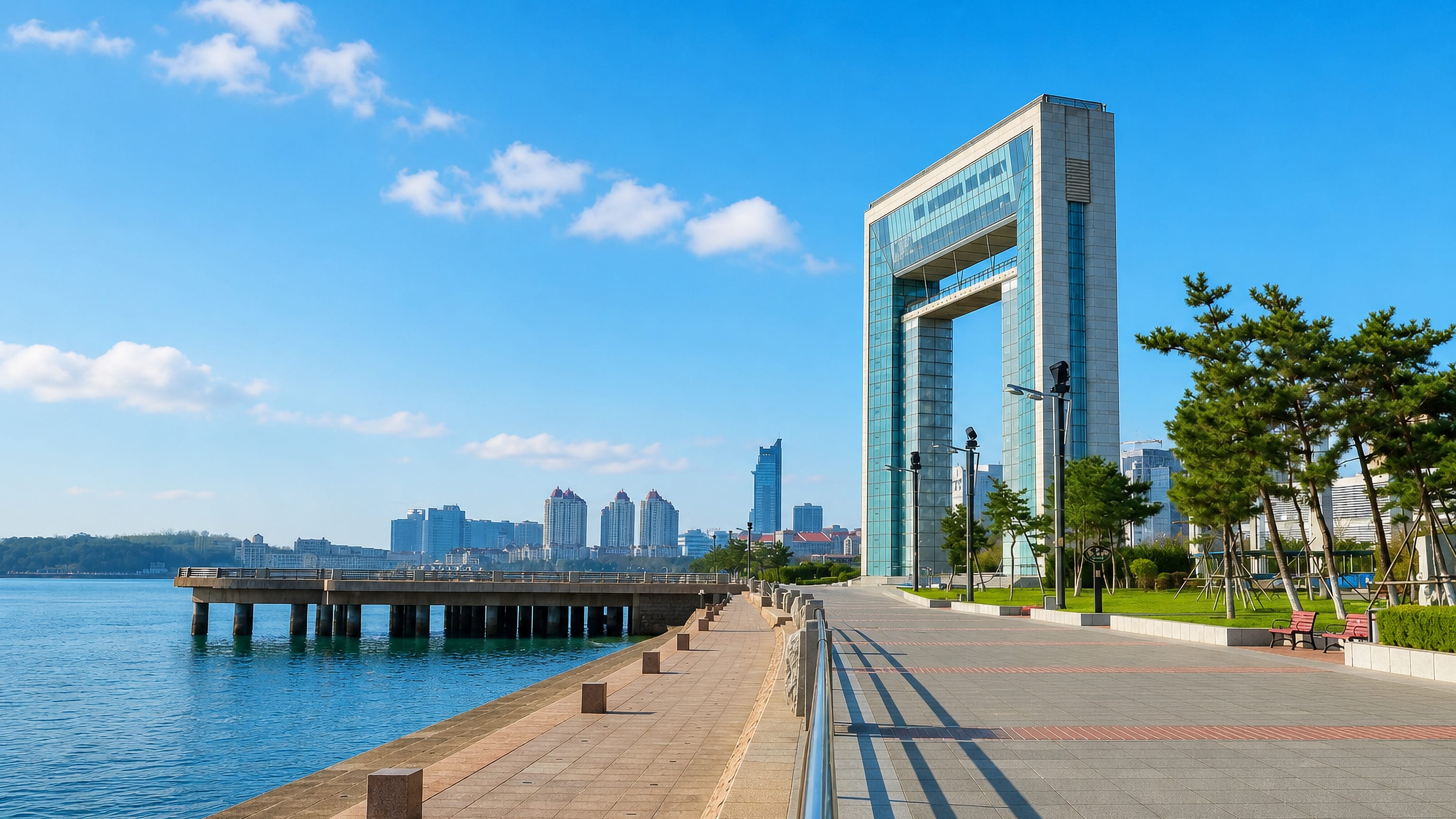 Weihai's arch-shaped Happiness Gate tower rising above the seafront promenade and pier in Shandong, China