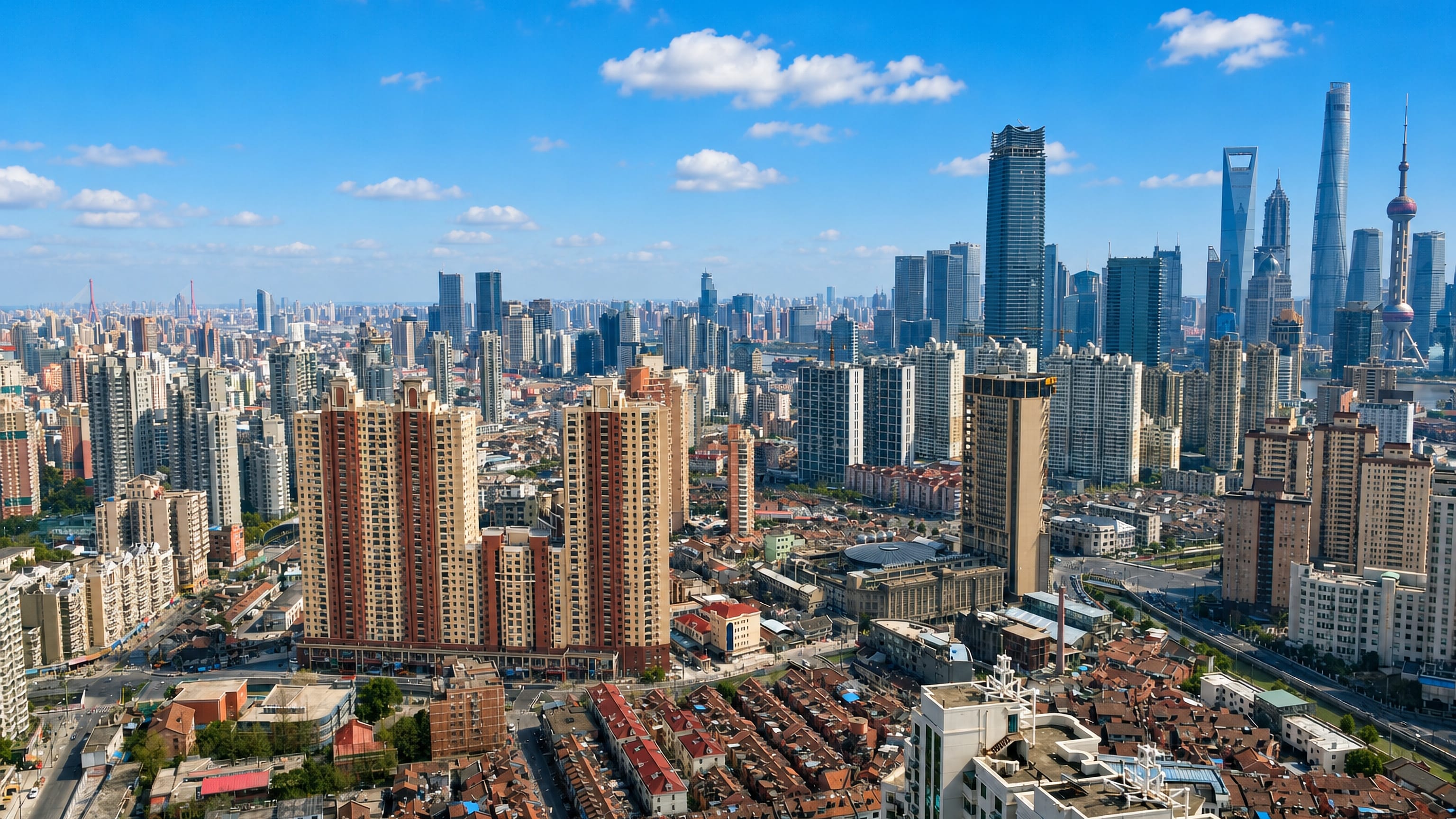 Lane-house rooftops and high-rises of Hongkou with Shanghai's Lujiazui towers on the horizon.
