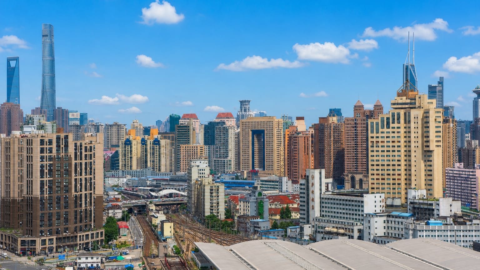 Jing'an rooftops with the Shanghai Tower and World Financial Center rising on the skyline beyond rail lines.