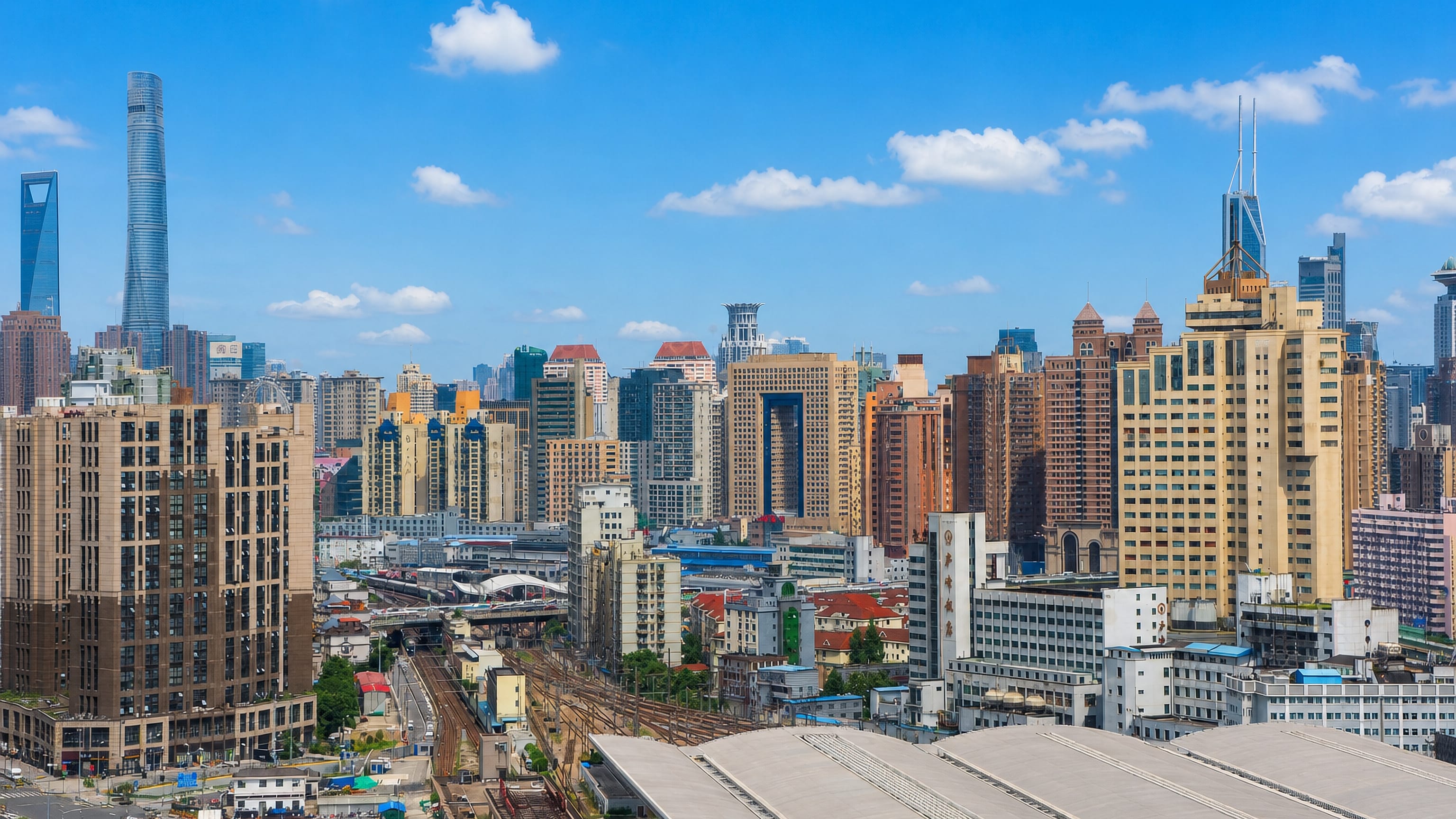 Jing'an rooftops with the Shanghai Tower and World Financial Center rising on the skyline beyond rail lines.