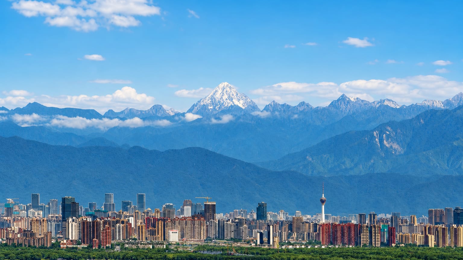 Chengdu's high-rise skyline and TV tower with snow-capped mountains rising behind under a blue sky.